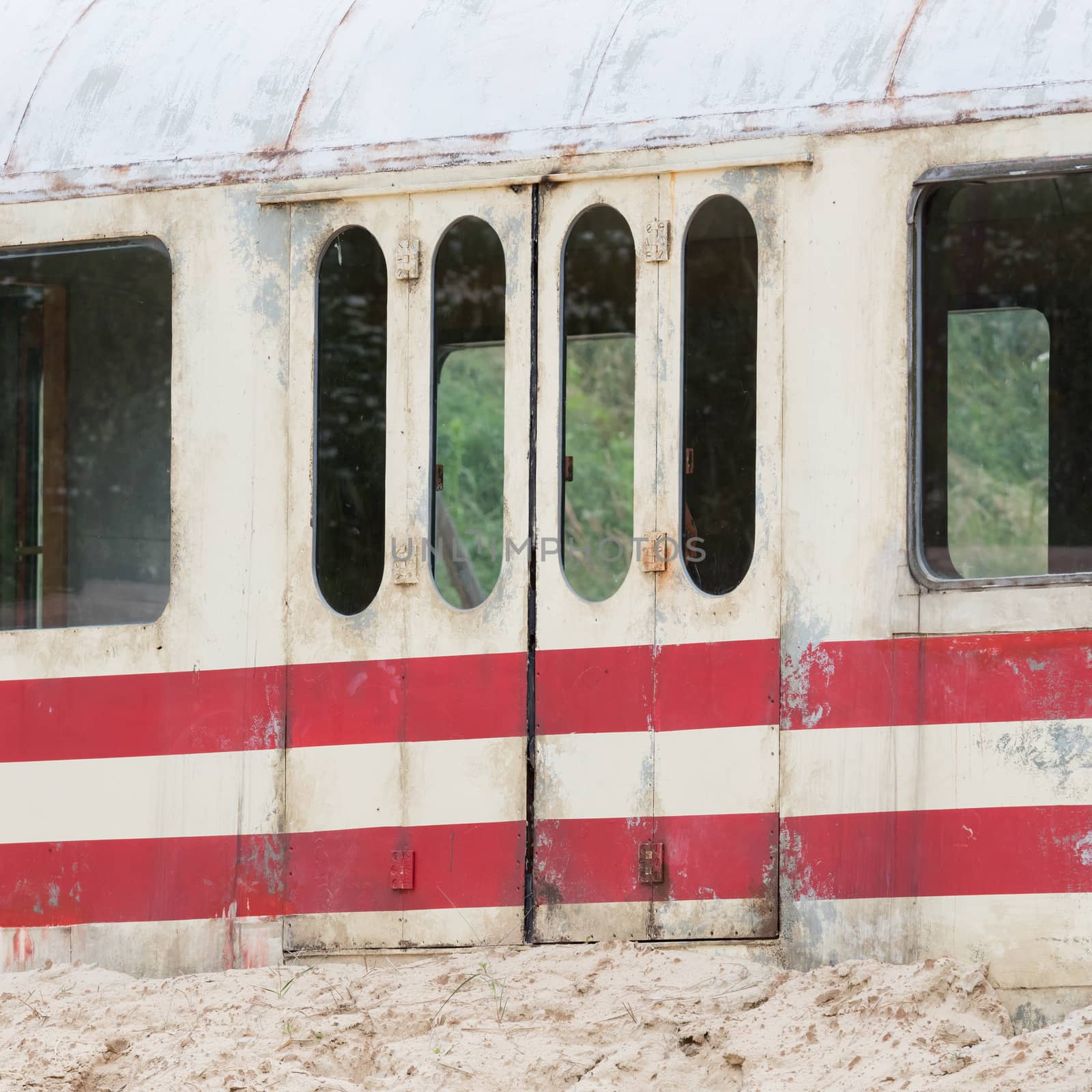 Old train carriage lying still in the rough sandy terrain