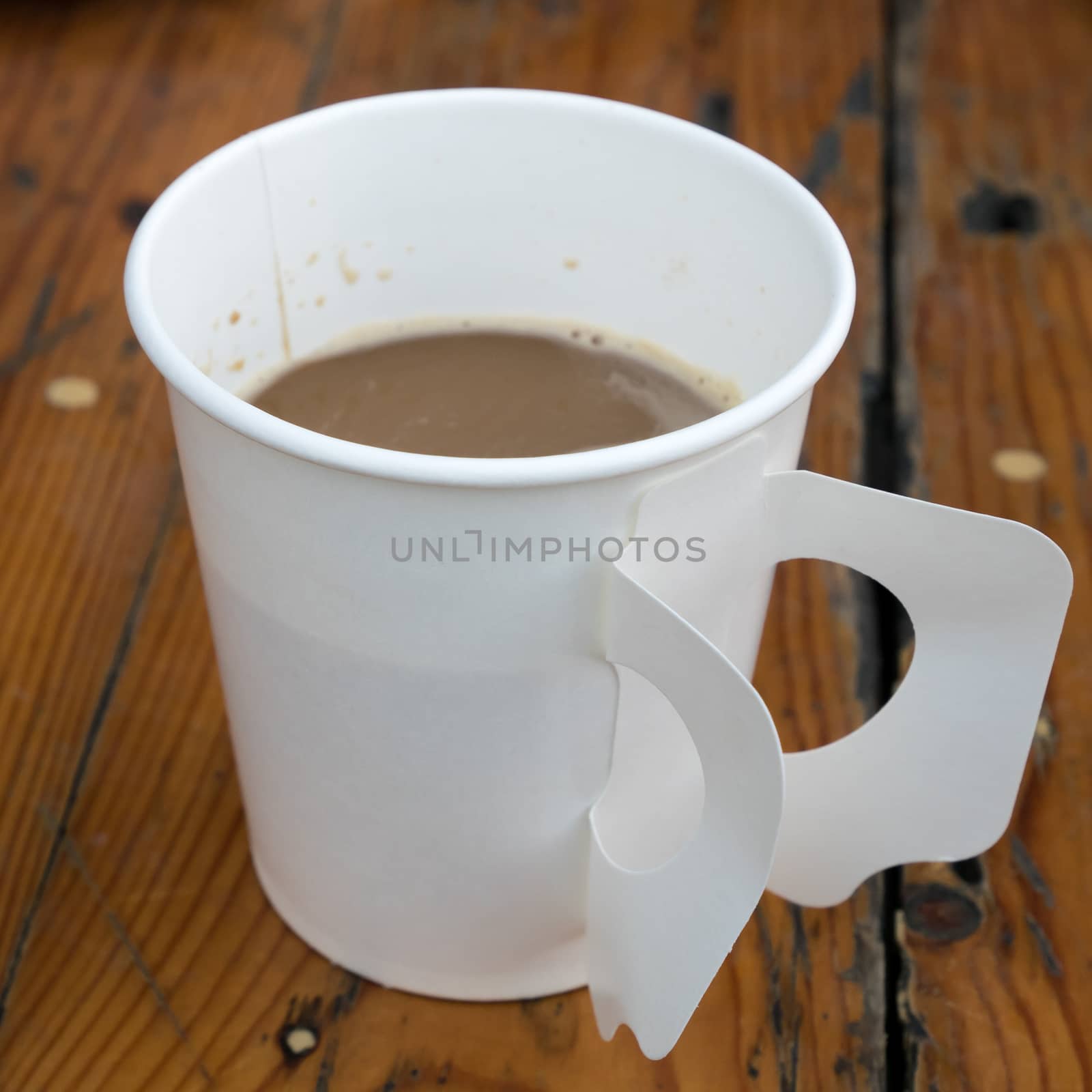 The paper cup of hot coffee on old wooden planks.