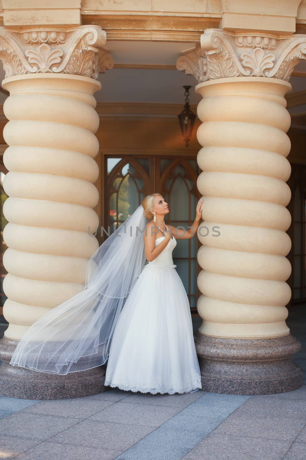 Bride with long veil standing near the column