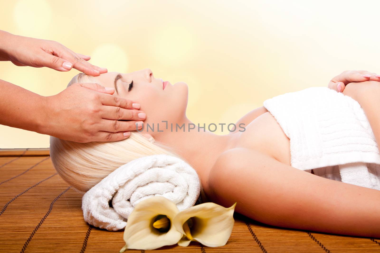 Beautiful young woman relaxing at spa getting therapeutic pampering forehead massage.