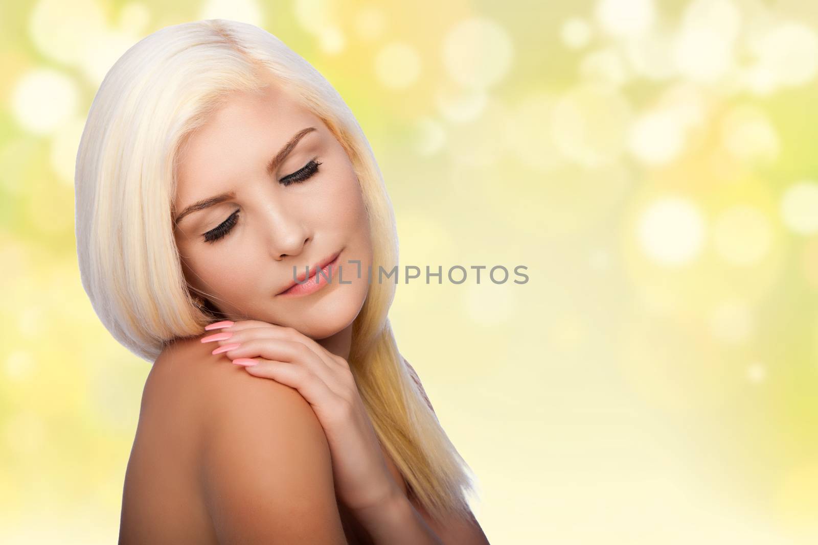 Beautiful face of young woman for Aesthetics facial skincare concept with eyes closed, hand on shoulder, on blurred lights background.