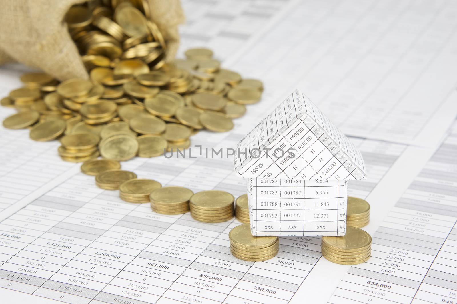 Close up house on pile of gold coins on finance account have blur gold coins overflow from brown sack as background.