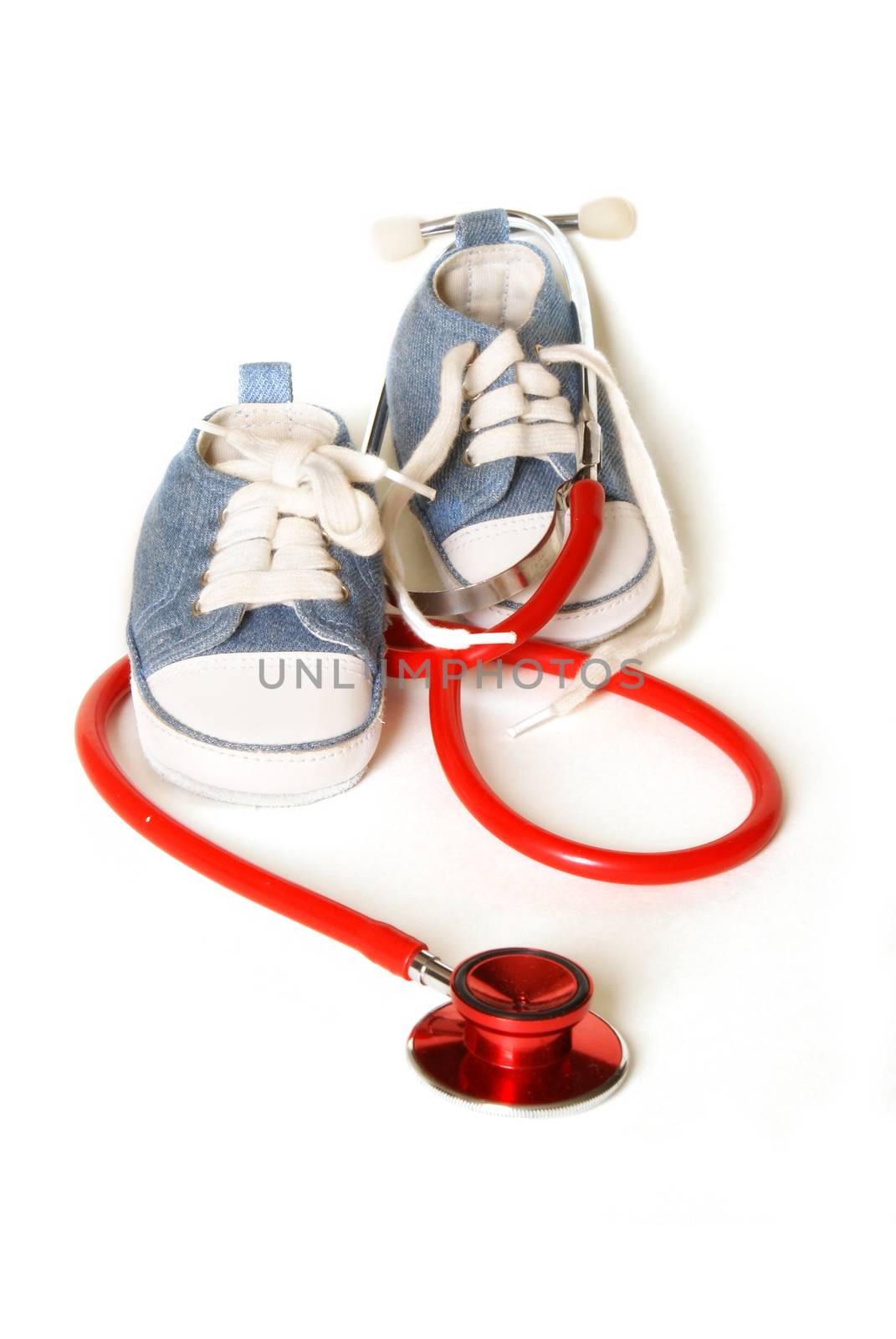 Isolated denim baby shoes and a doctors stethoscope representing childcare prediatrics.