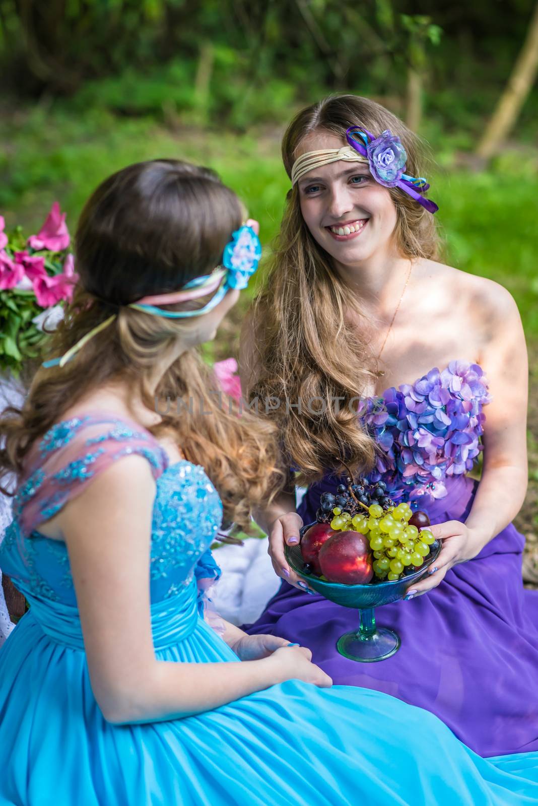 Beautiful happy smiling sisters twins in the garden with flowers and still life