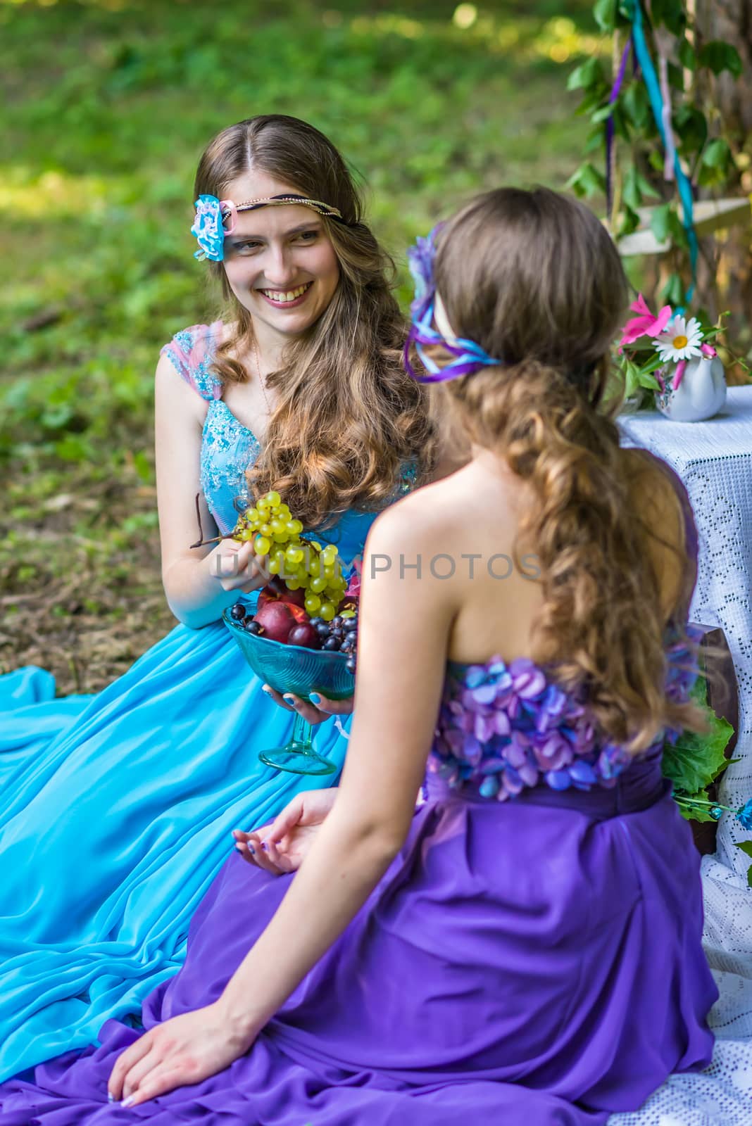 Beautiful happy smiling sisters twins in the garden with flowers and still life