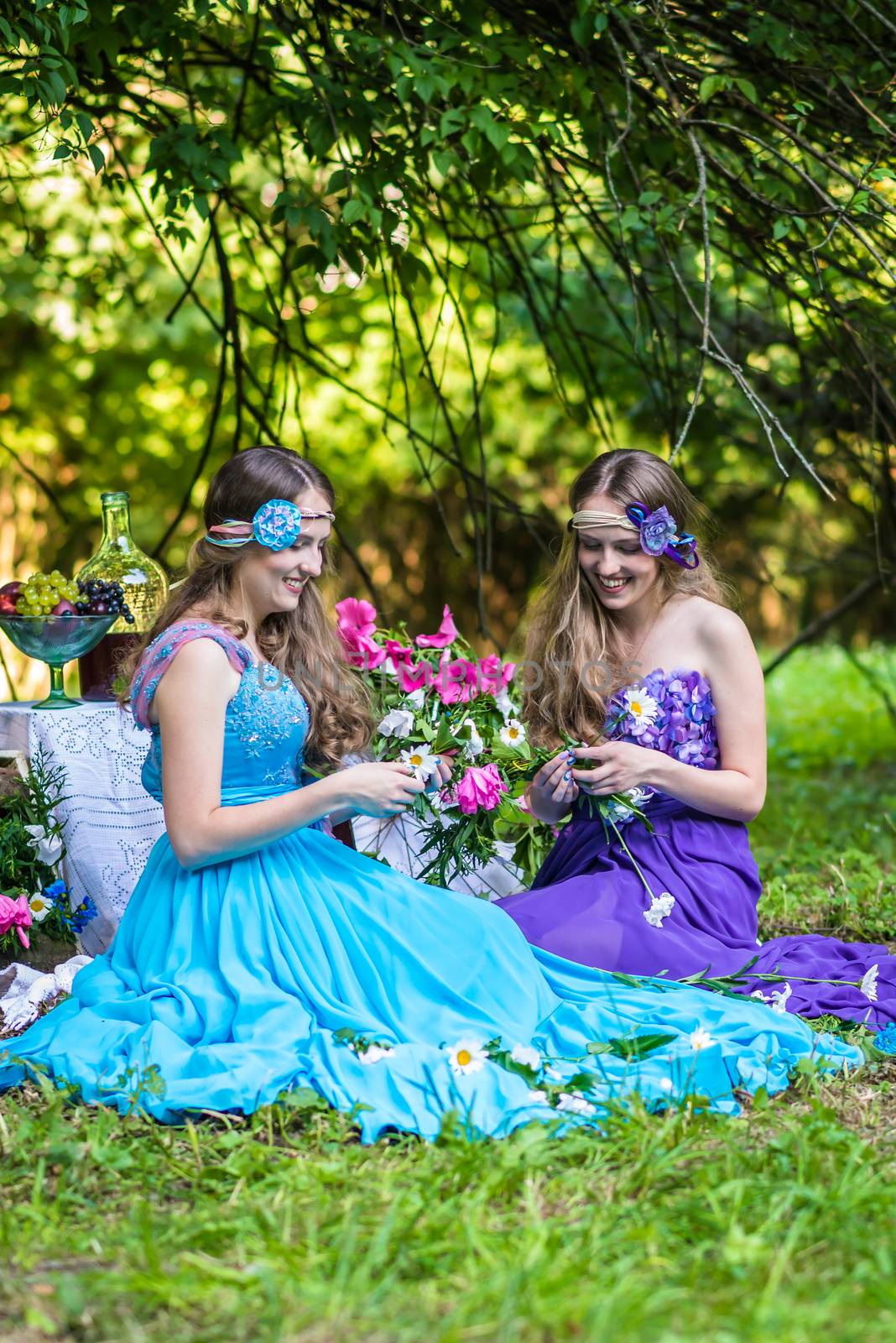 Beautiful happy smiling sisters twins in the garden with flowers and still life