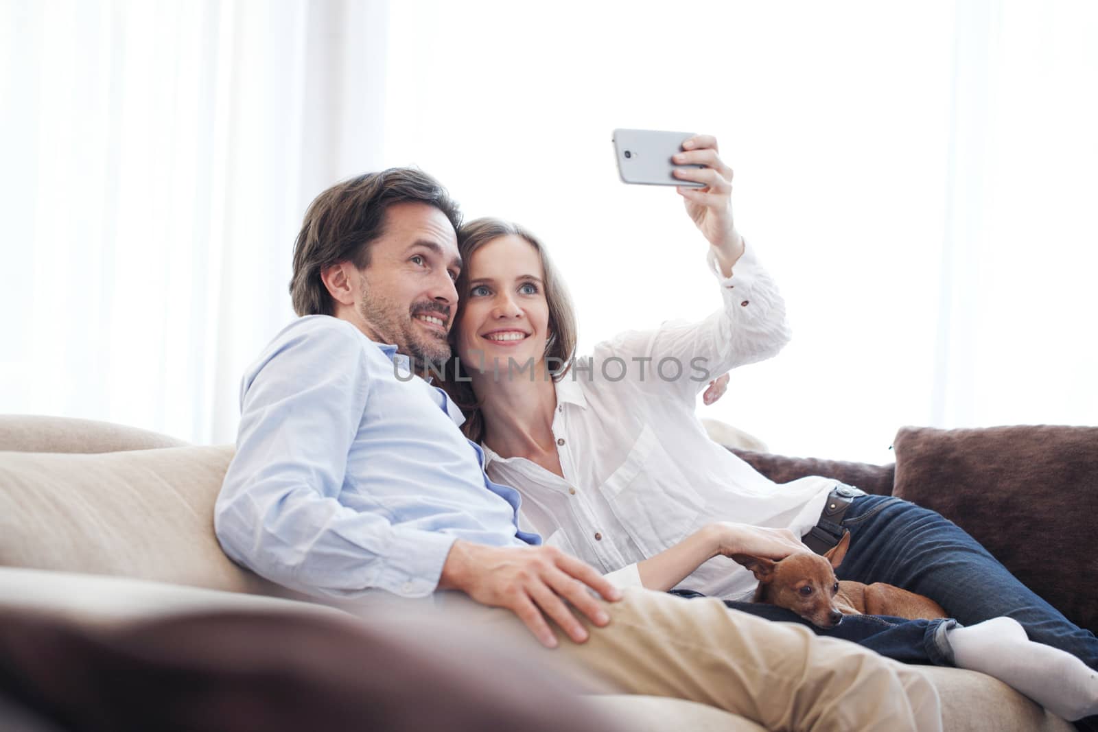 Happy couple taking a selfie together on the couch at home