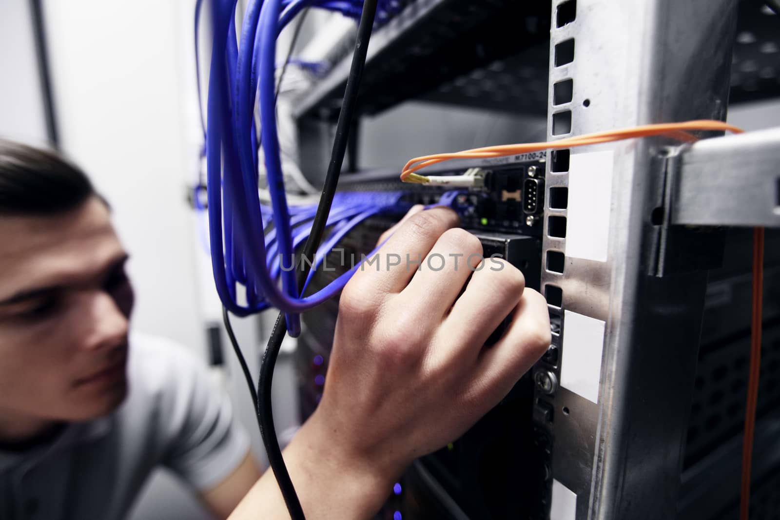 Young engeneer man in network server room connecting wires