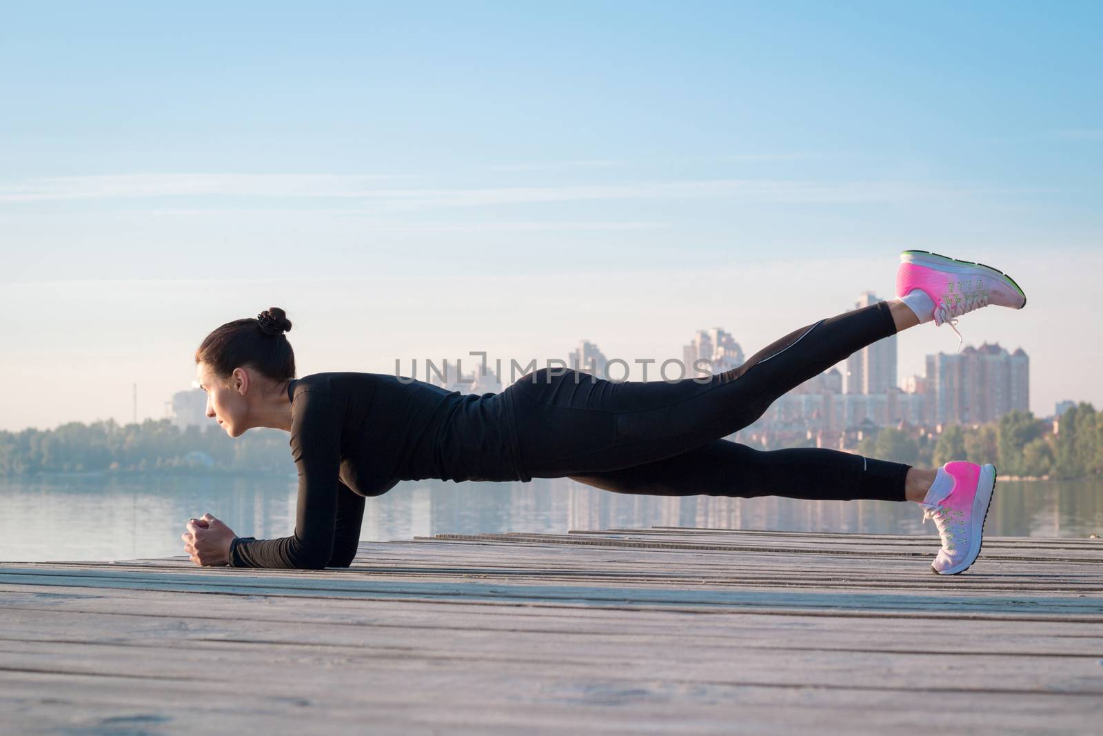 Pretty fitness woman exercises on pier during sport training by VeraVerano