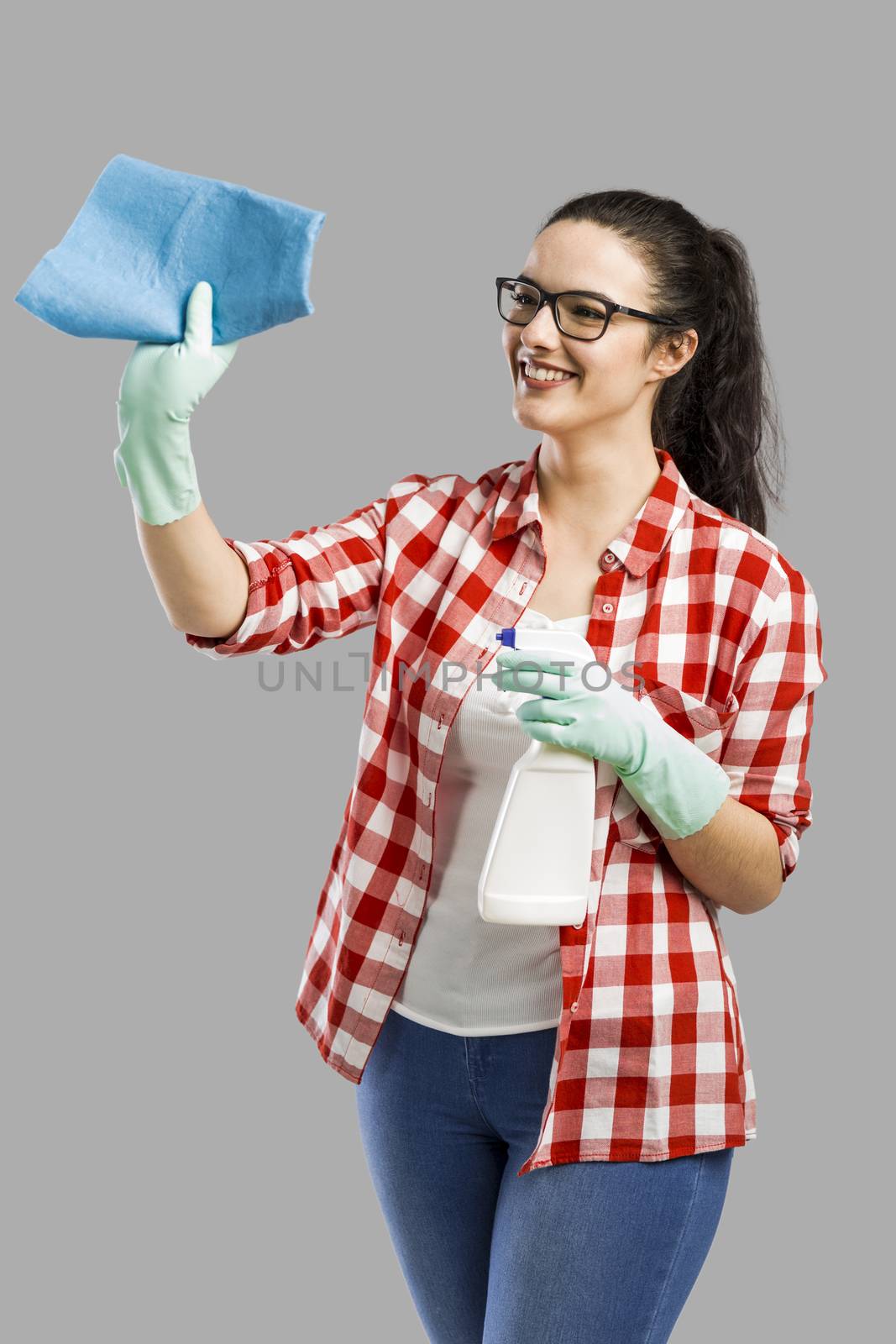 Pretty woman wearing gloves, using a cleaning spray and cleaning the house