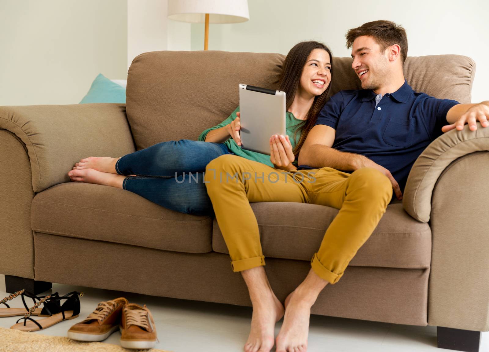 Young couple sitting on the sofa and watching something on a tablet