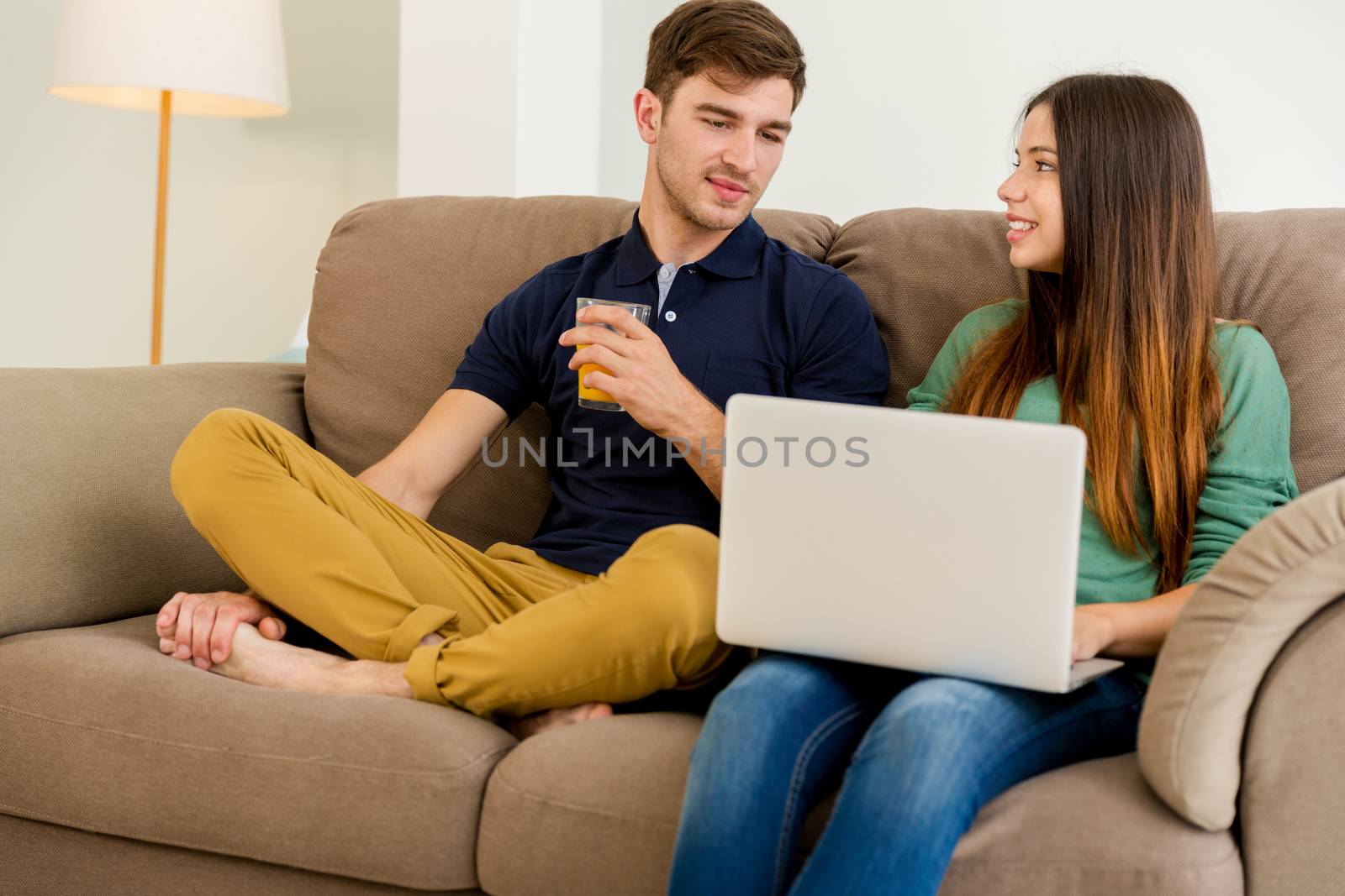 Young couple sitting on the sofa and watching something on a laptop