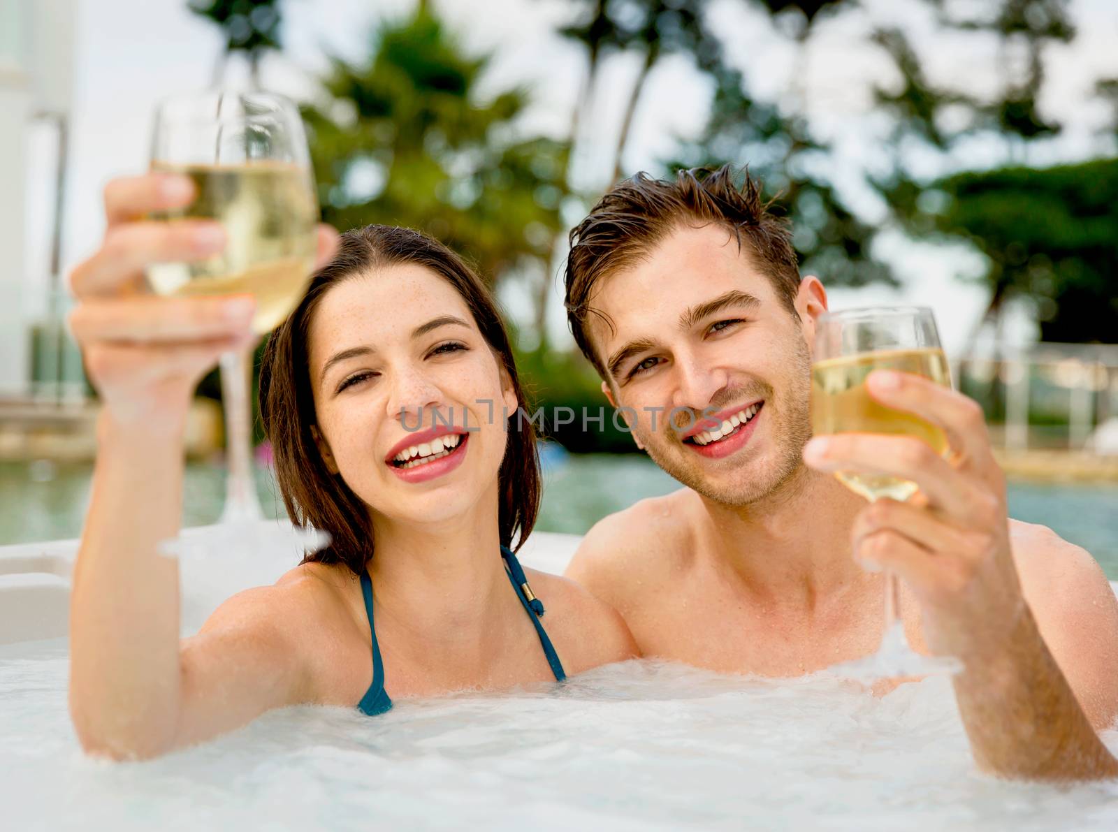 Young couple inside a jacuzzi and toasting 