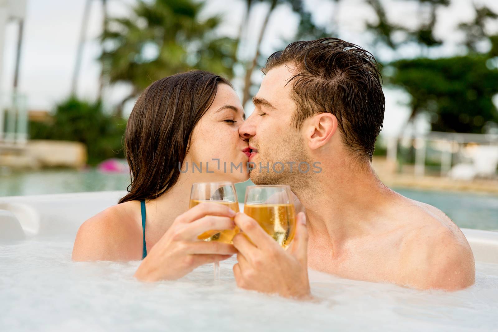 Young couple inside a jacuzzi dating and toasting 