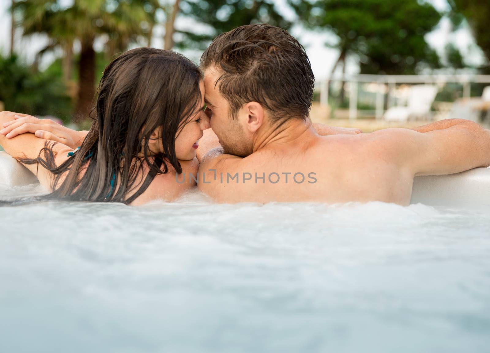 Young couple in a luxury hotel  inside a jacuzzi and kissing