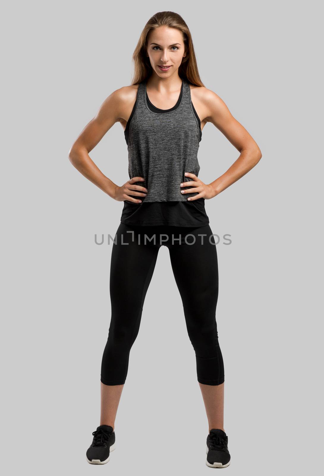 Young fitness woman against a gray background