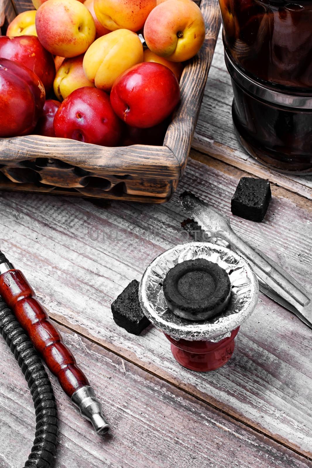 Smoking Arab hookah and wooden basket with plums