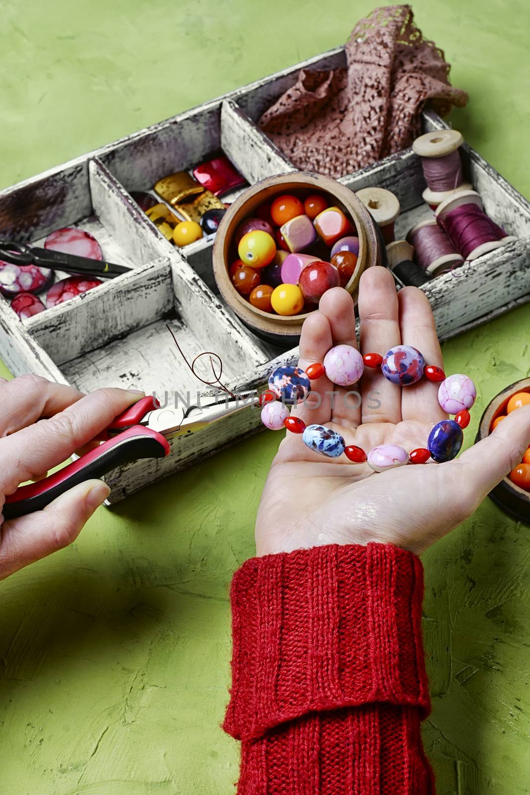 drawer with beads and female hands collecting bracelet for the hand