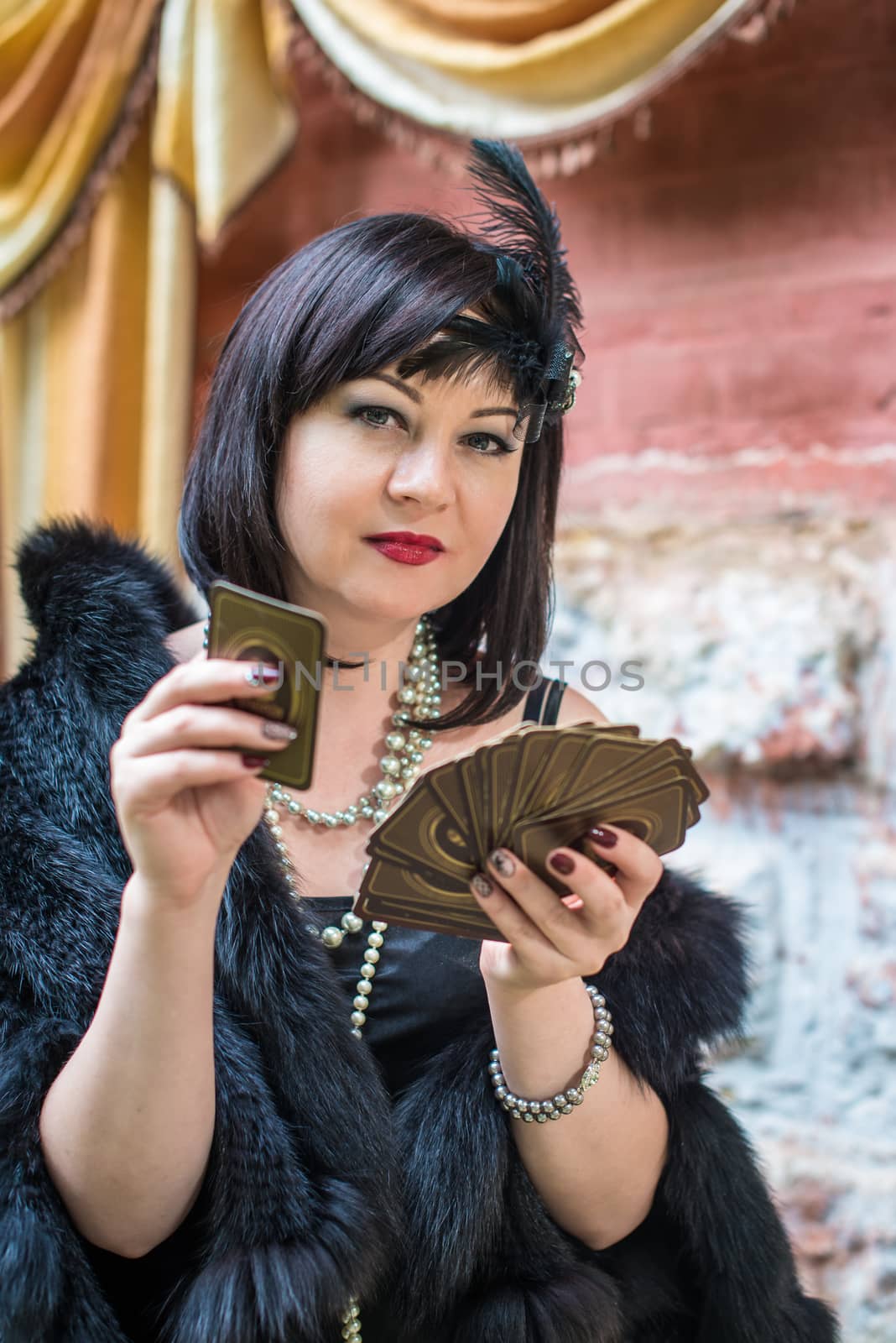 Beautiful retro woman in a black dress holding playing cards