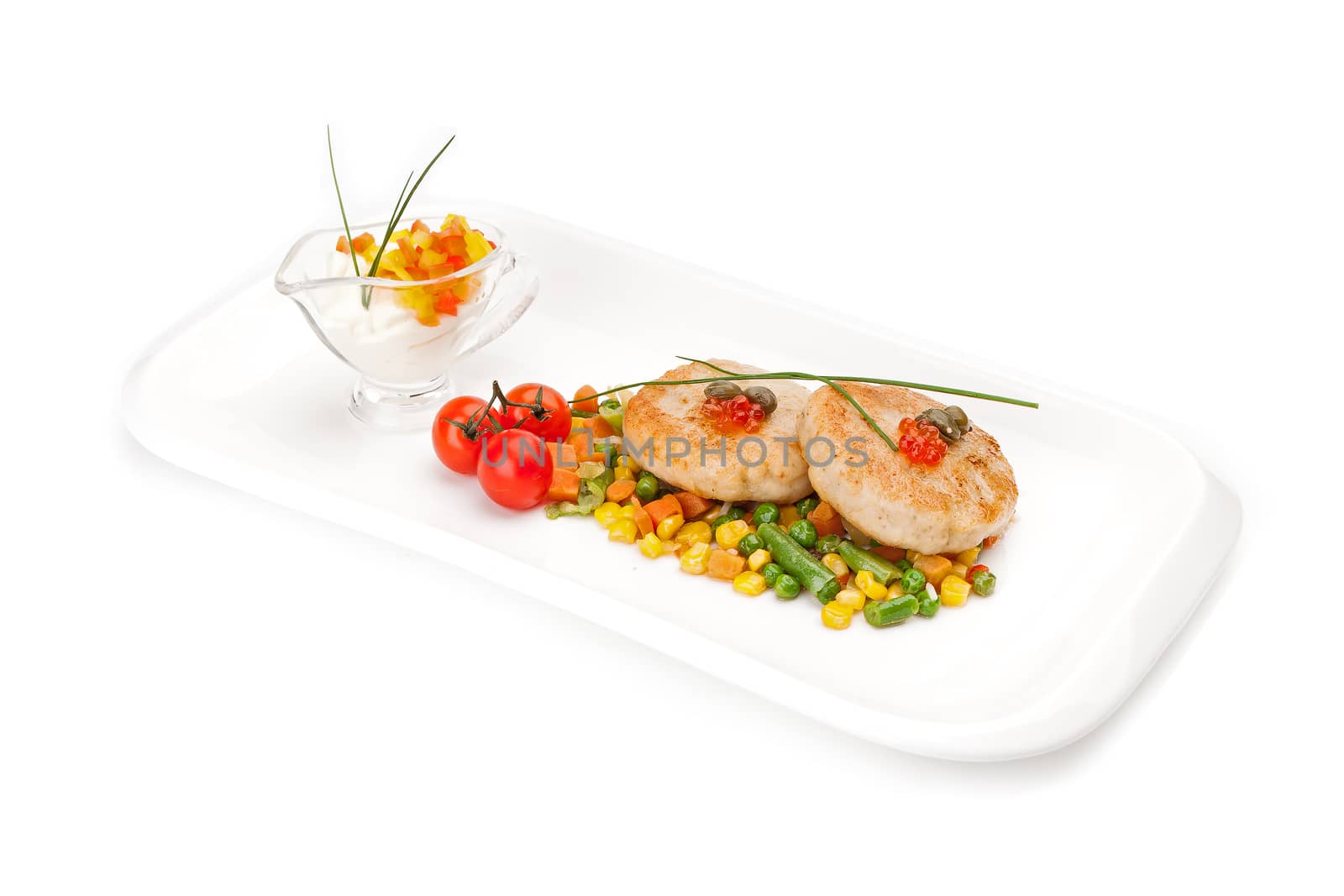 The dietary fish cutlets served on a white dish with a garnish from corn and asparagus haricot, with sauce, decorated by red caviar,  isolated on a white background.