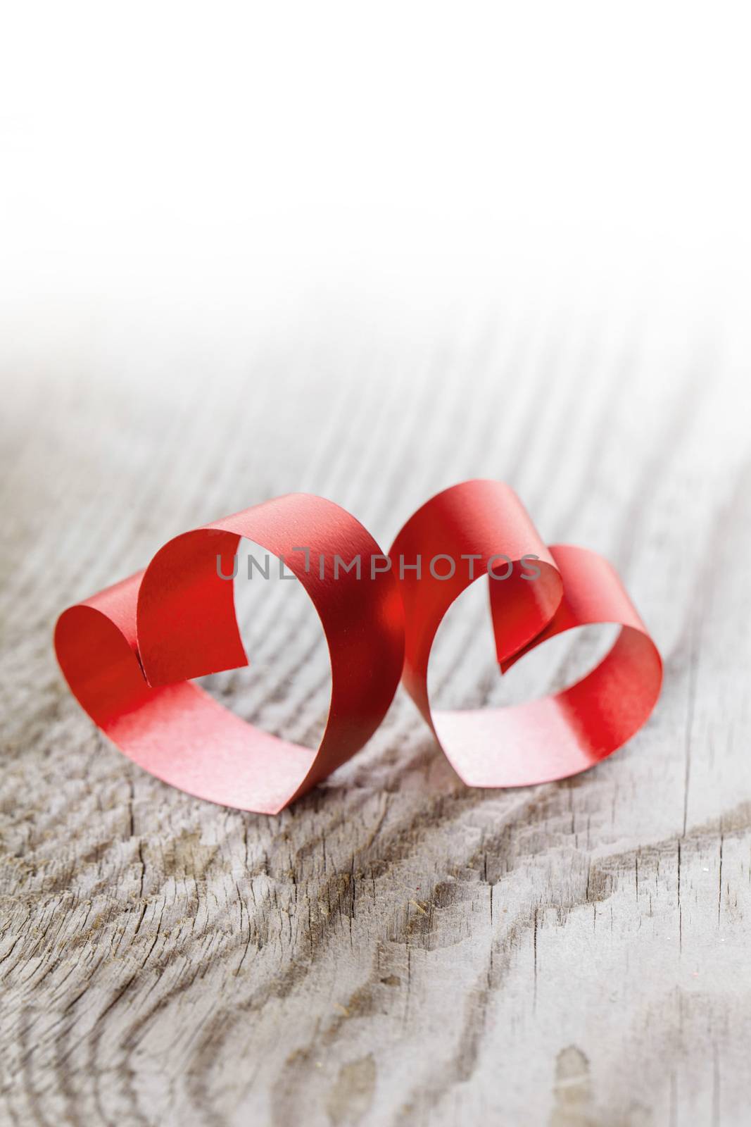 Two red small ribbon hearts on wooden background