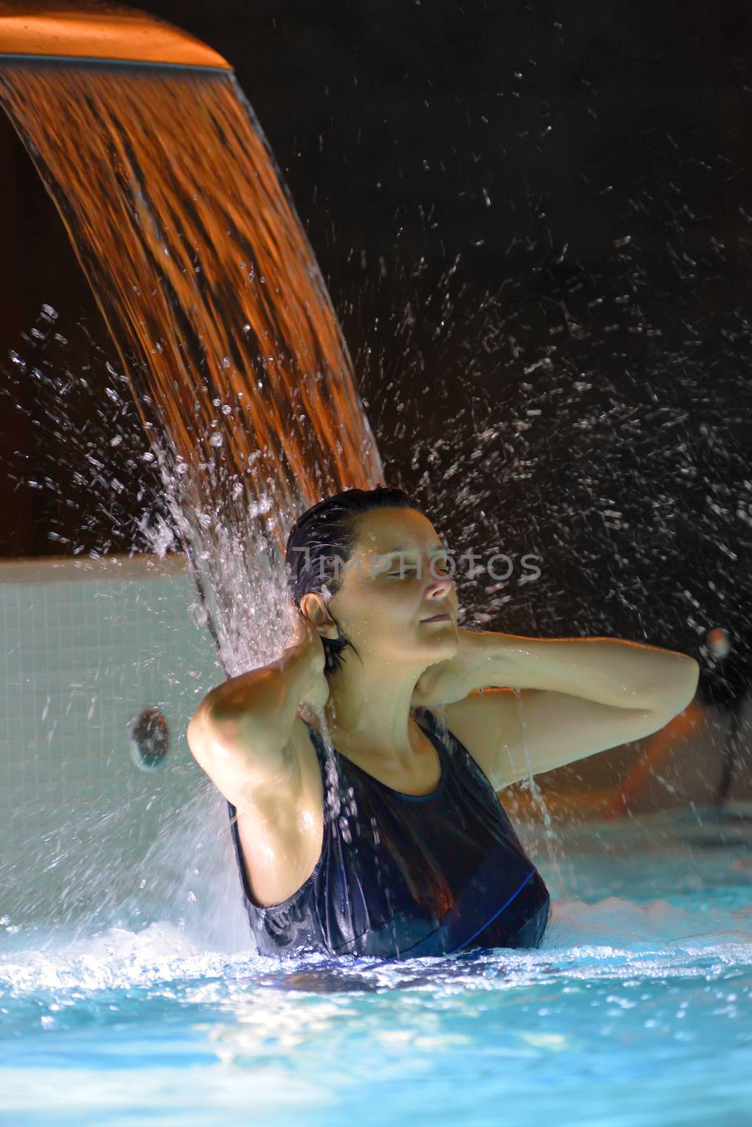 Woman relaxation in pool with waterfall