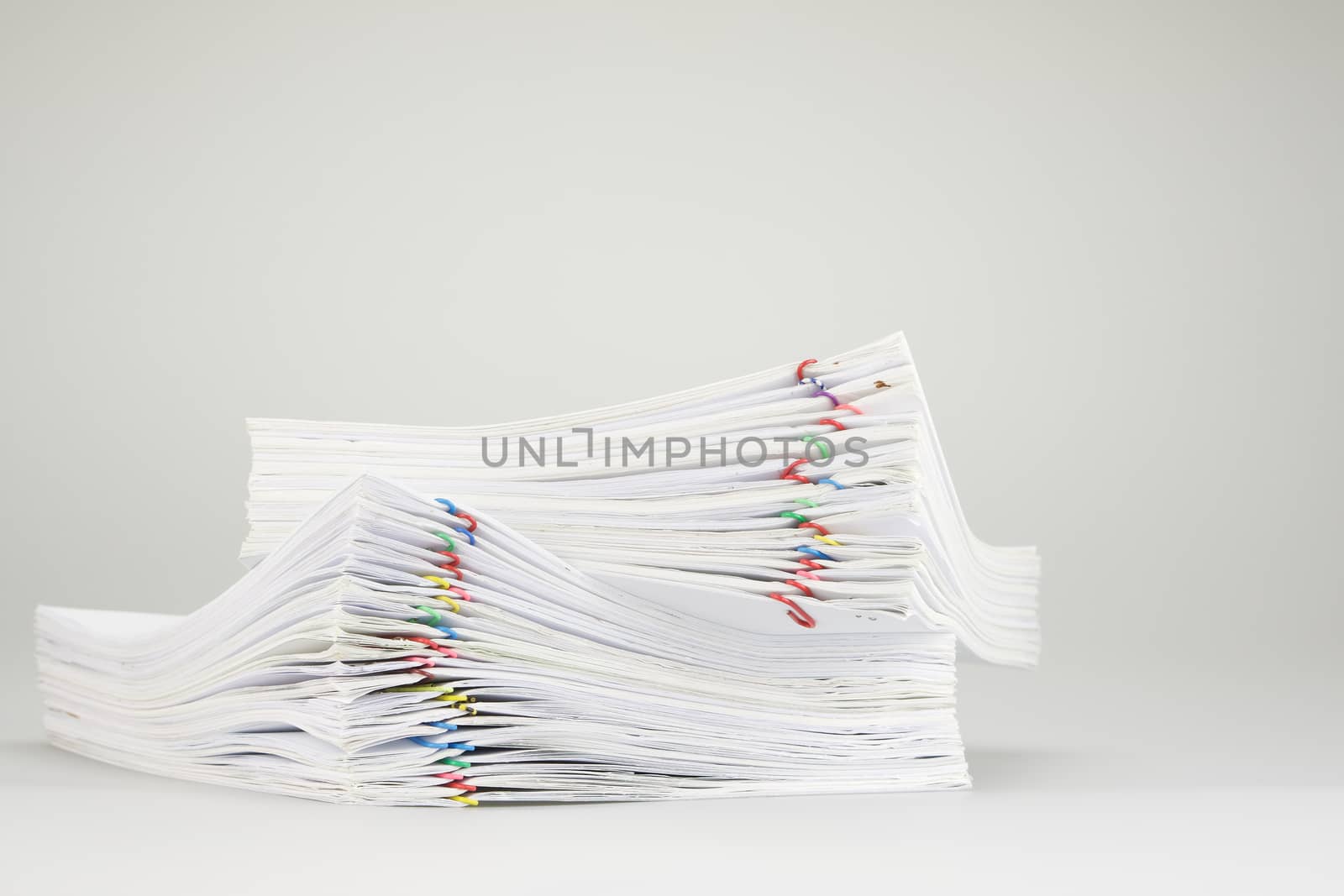 Pile overload of paperwork with colorful paper clip place on white background.