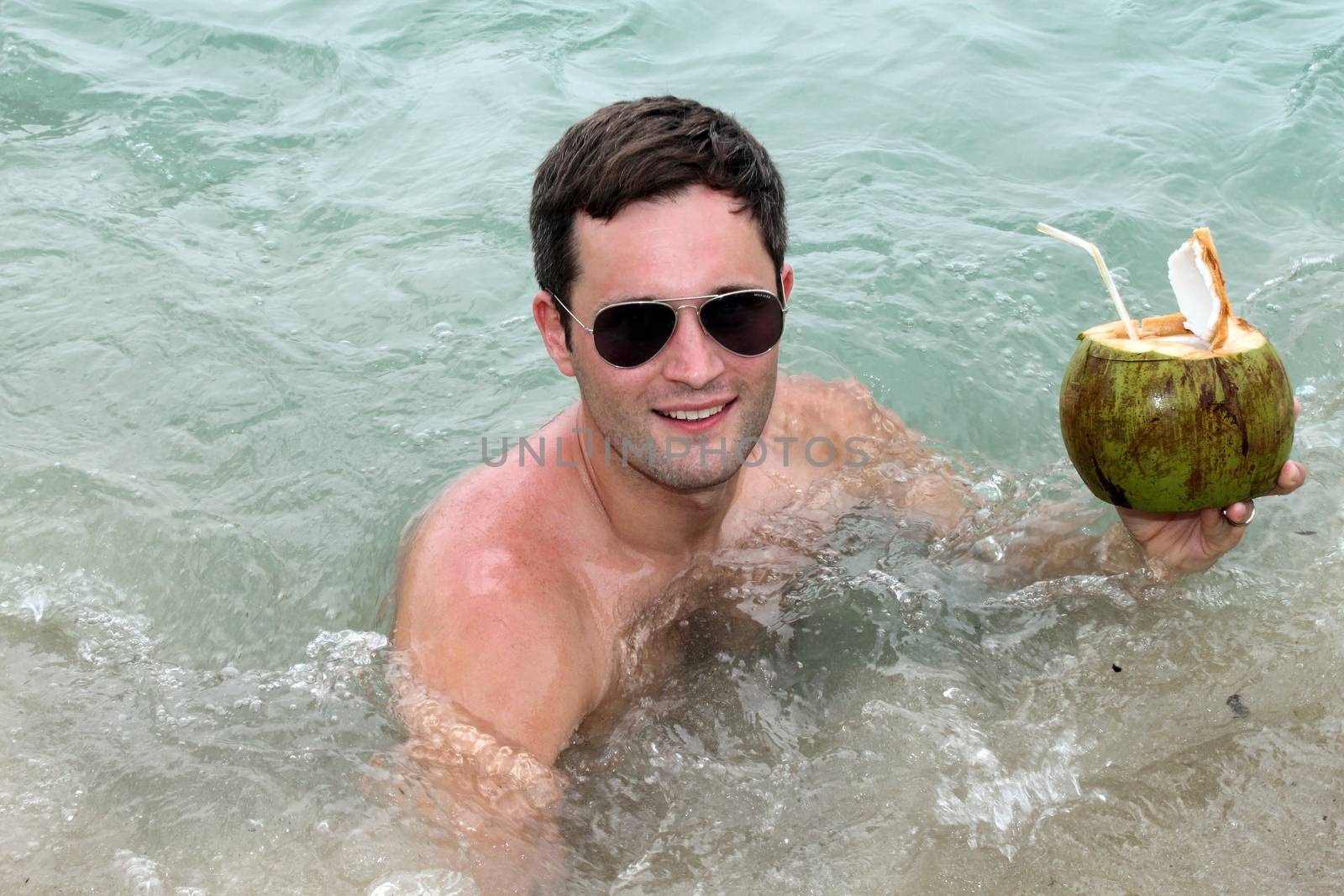 a happy Boy man drinking coconut juice in pool or in the sea water