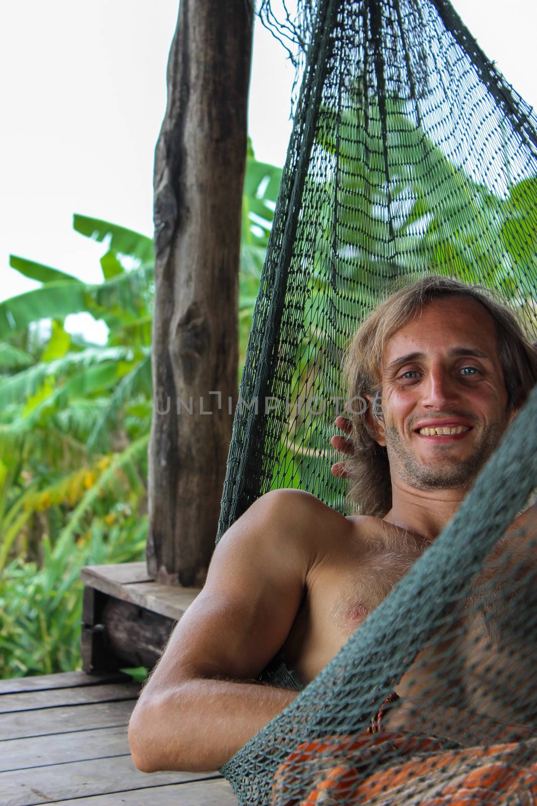 casual happy man relaxing on a hammock in the beach holidays by evolutionnow