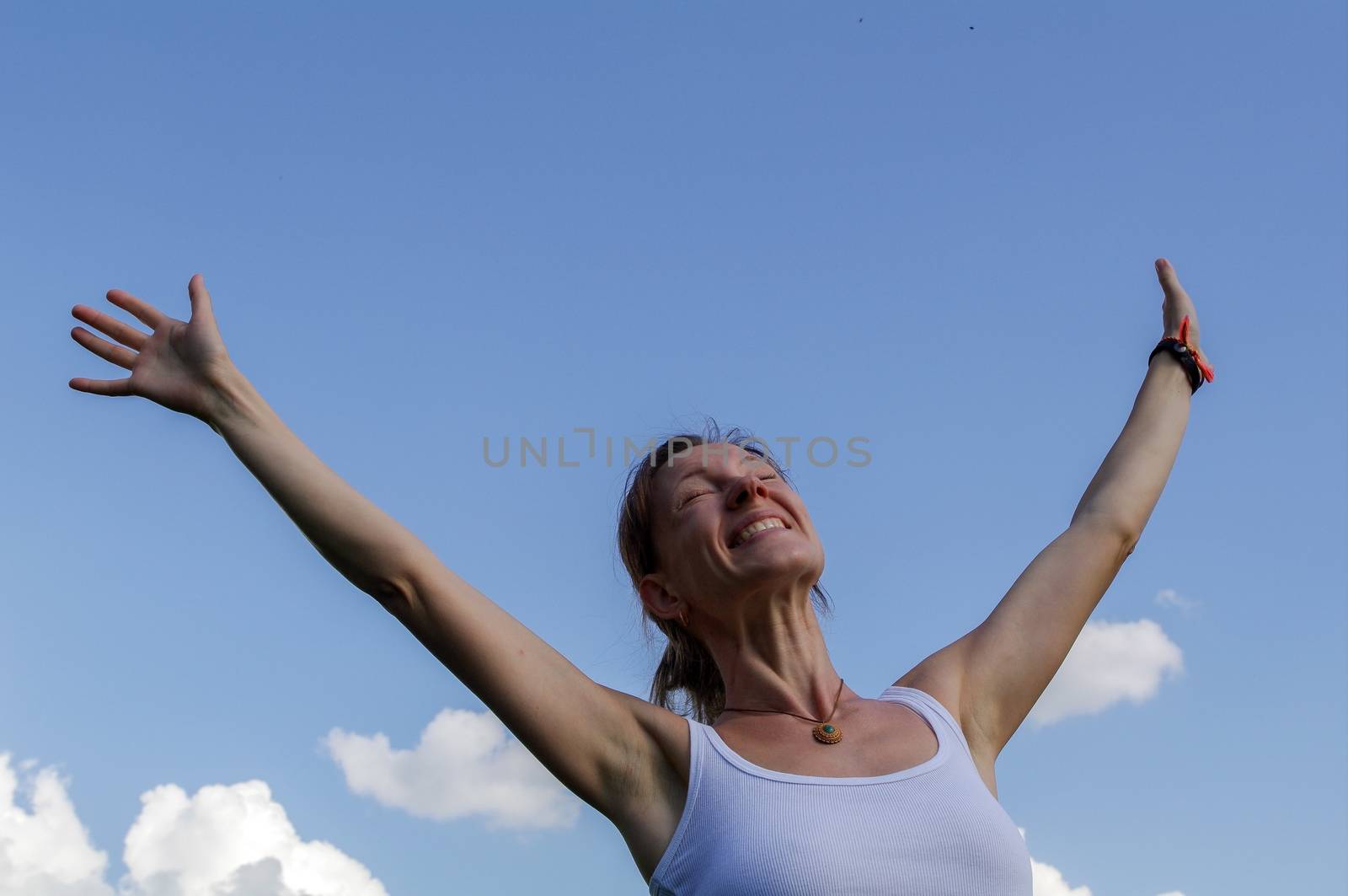 young woman raise or stretches her hands towards the sky by evolutionnow