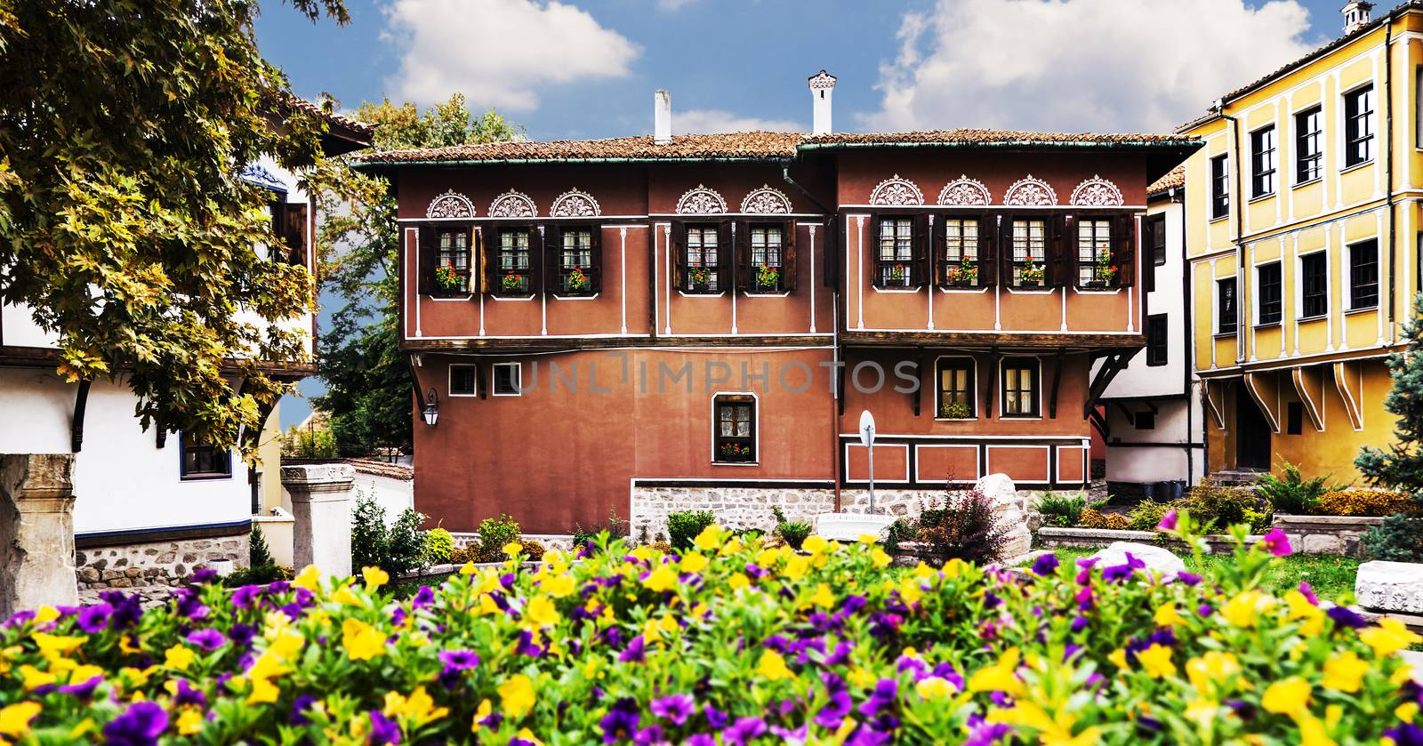 Old houses, cultural heritage in old town Plovdiv, Bulgaria with blooming flowers in foreground.