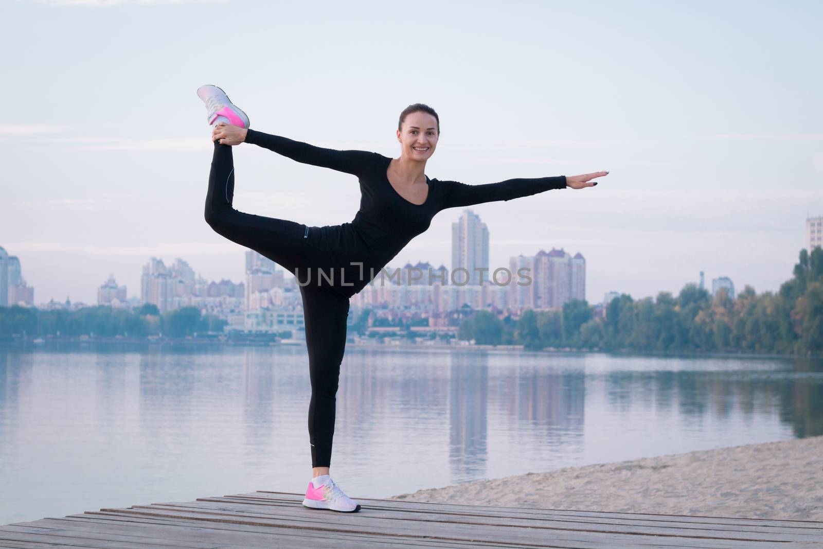 Young woman exercises on pier during morning training workout by VeraVerano