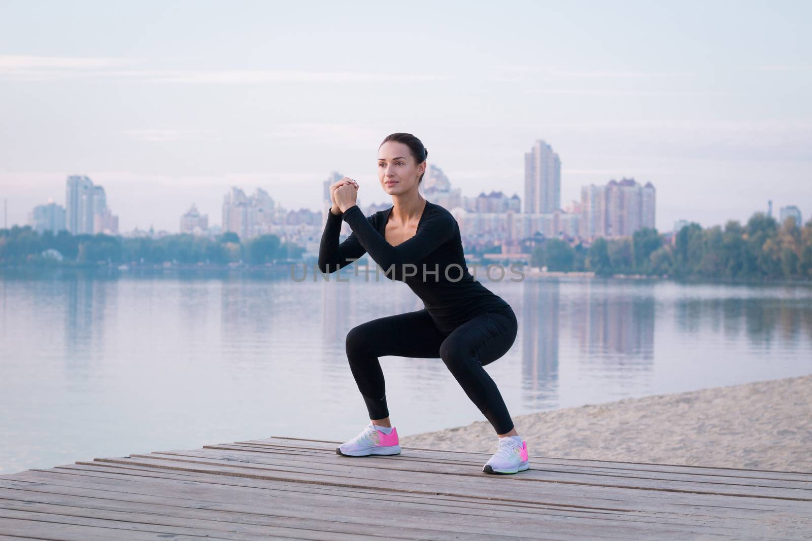 Young woman exercises on pier during morning fitness  by VeraVerano
