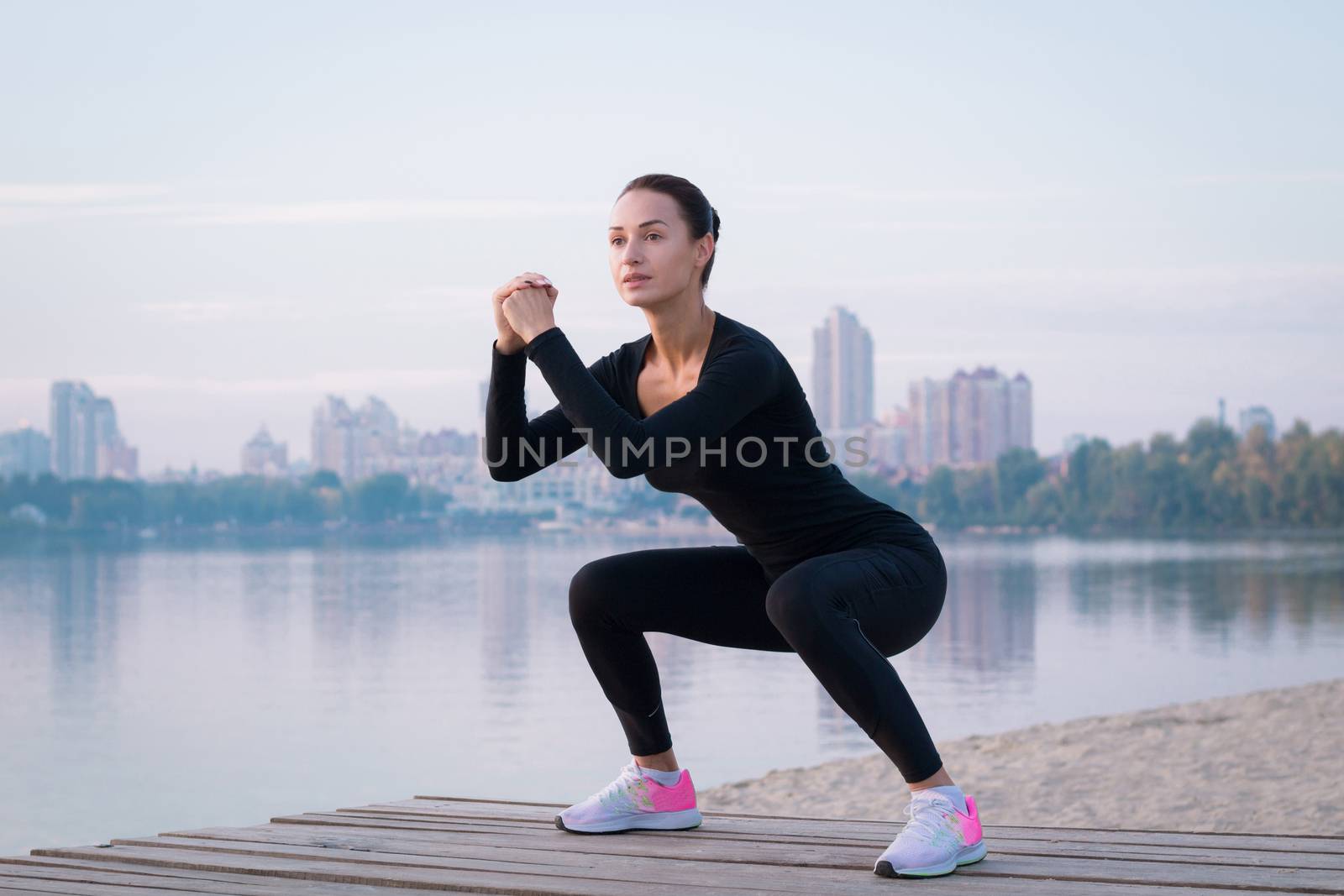 Young woman exercises on pier during morning training  by VeraVerano
