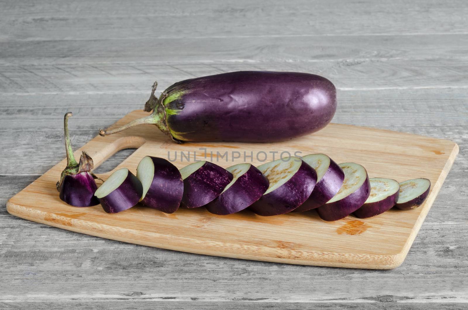 Eggplant lay on a cutting Board, on a gray wooden background.