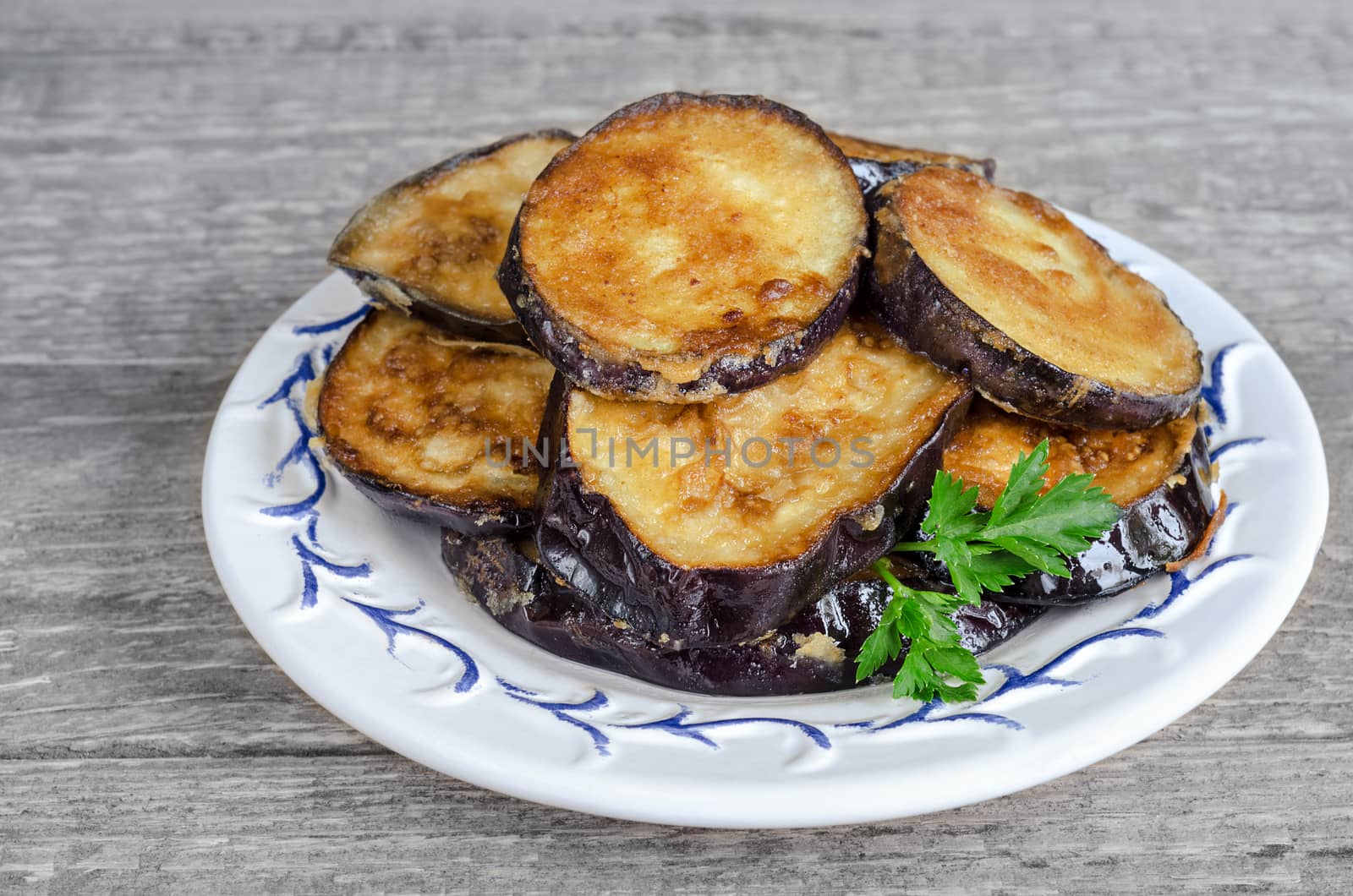 Fried eggplant, on the plate and a gray wooden background by Gaina