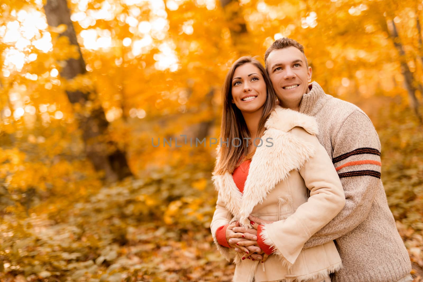 Beautiful lovely couple enjoying in sunny forest in autumn colors.