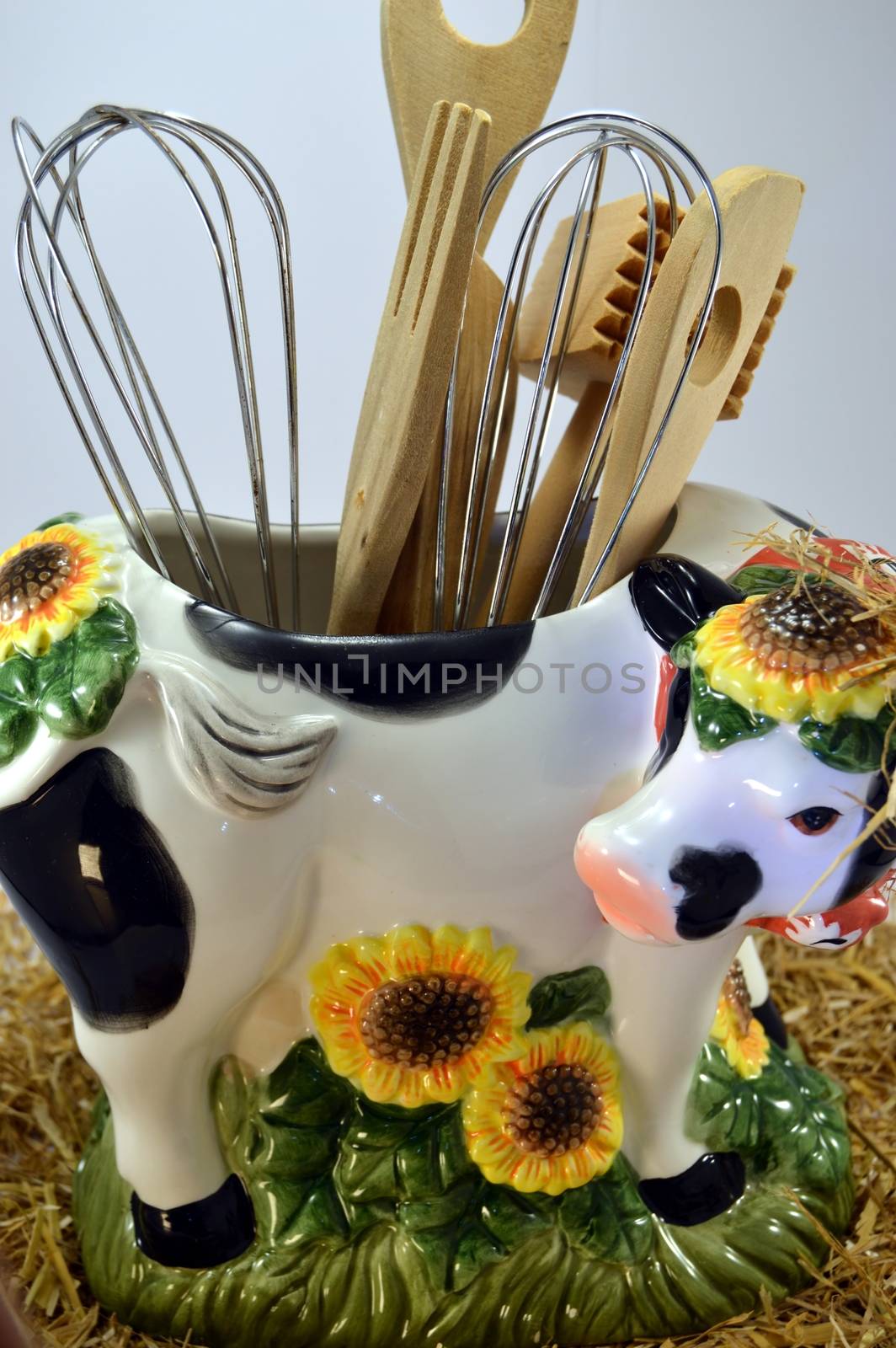 Distort cow with the hollow back and the kitchen utensils on a white bottom