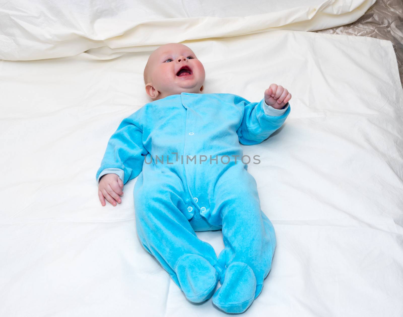 Four month old baby smiling while lying on the bed