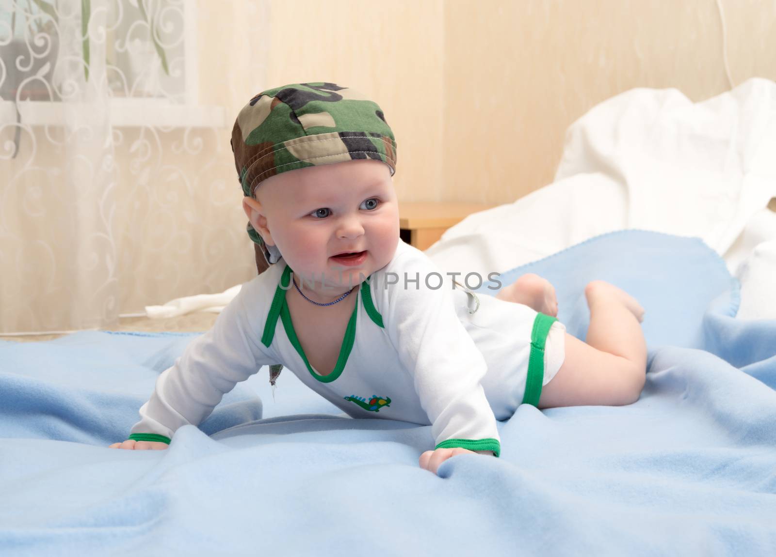 Kid in the camouflage bandana plays lying on his stomach