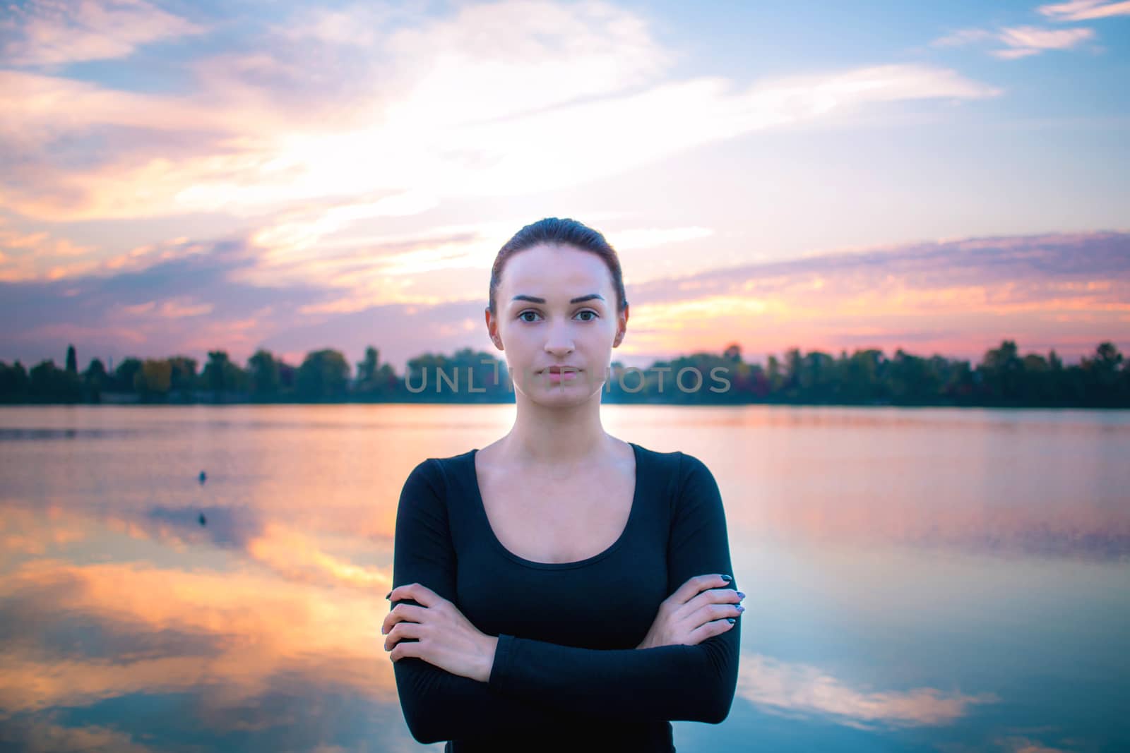 Young pretty woman portrait in early morning at colorful sunrise background