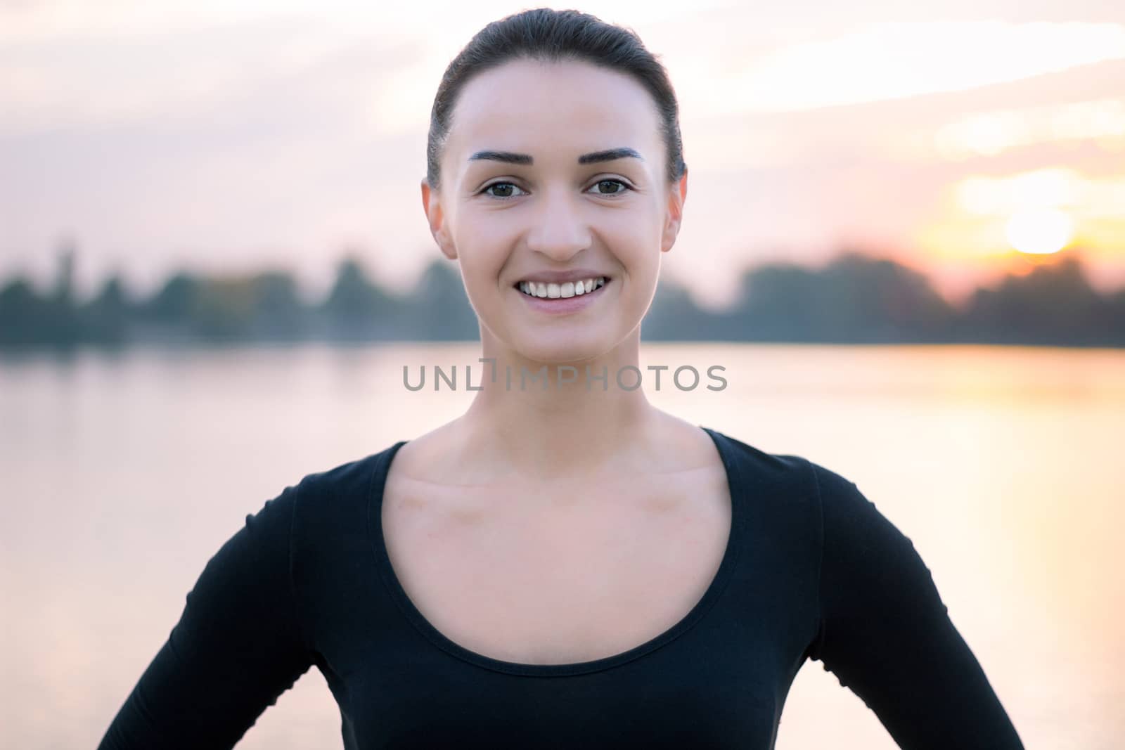 Young pretty woman portrait in early morning at colorful sunrise background