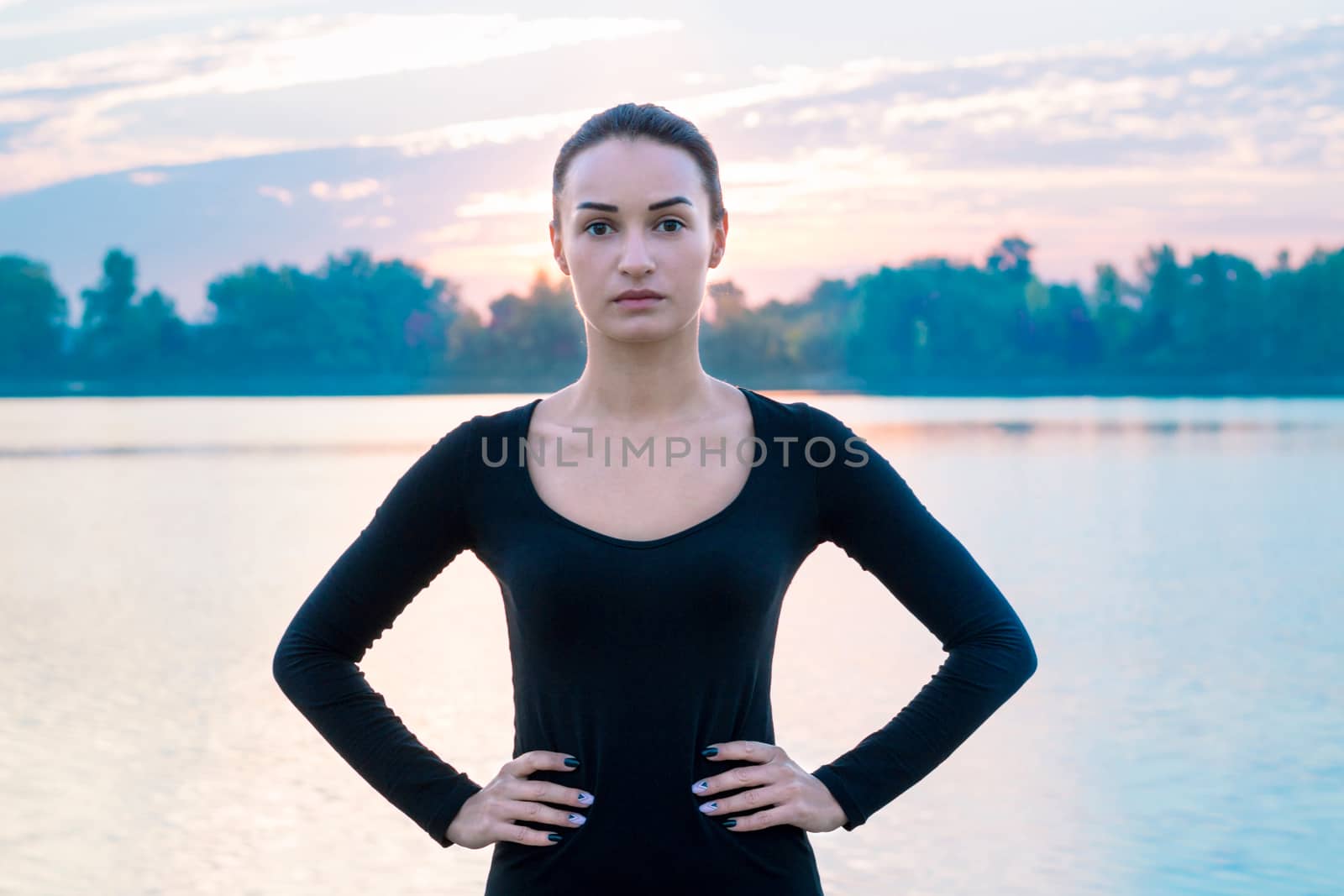 Young pretty woman portrait in early morning at colorful sunrise background