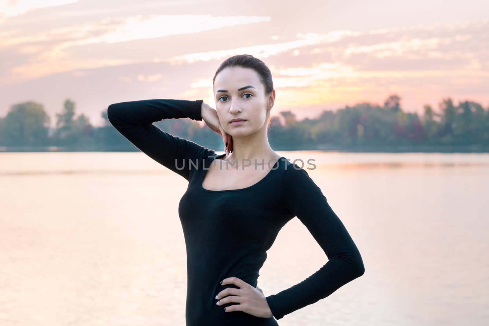 Young pretty woman portrait in early morning at colorful sunrise background