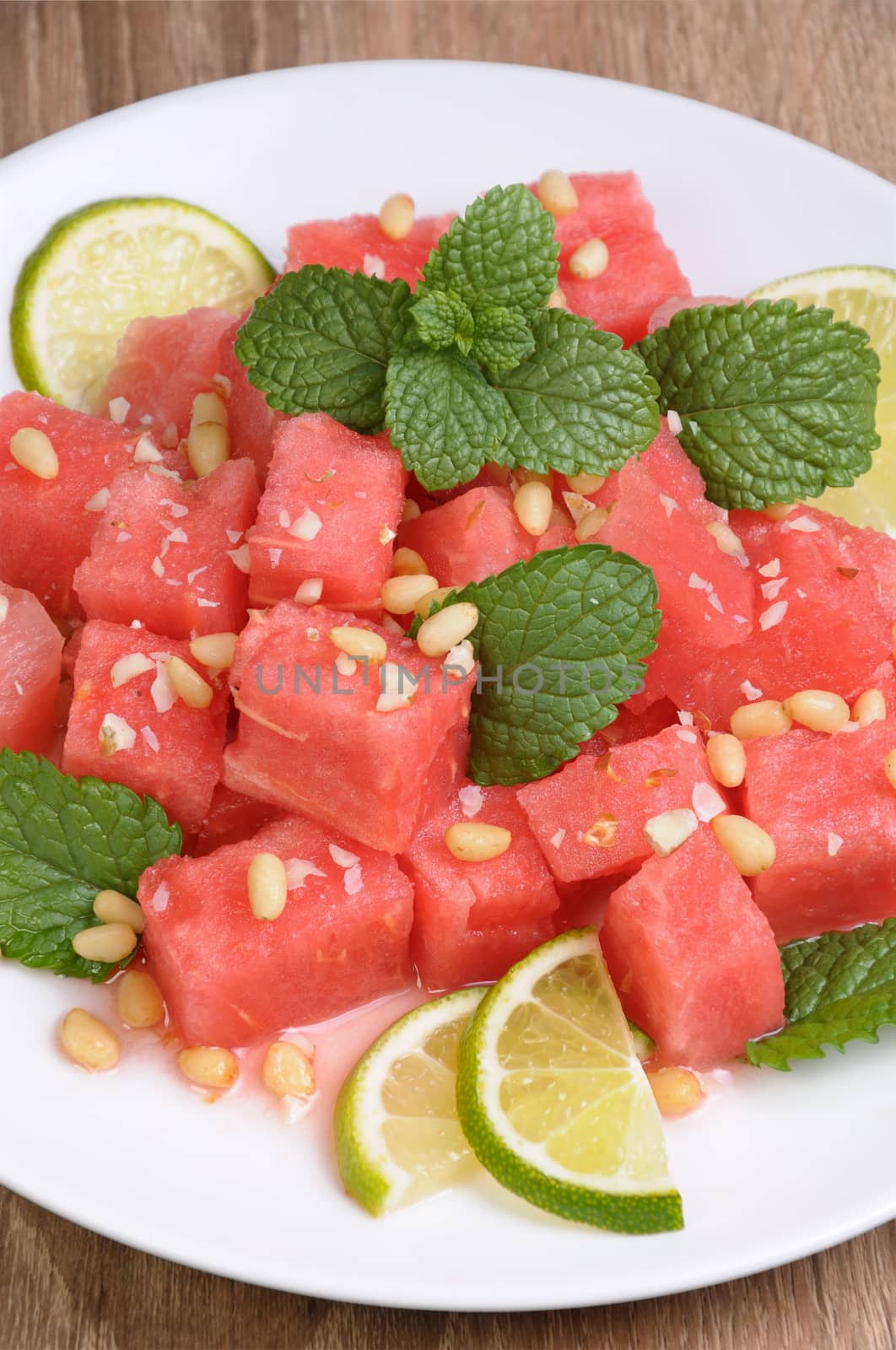 A refreshing salad of watermelon cubes with slices of lime, mint, peanuts, pine nuts
