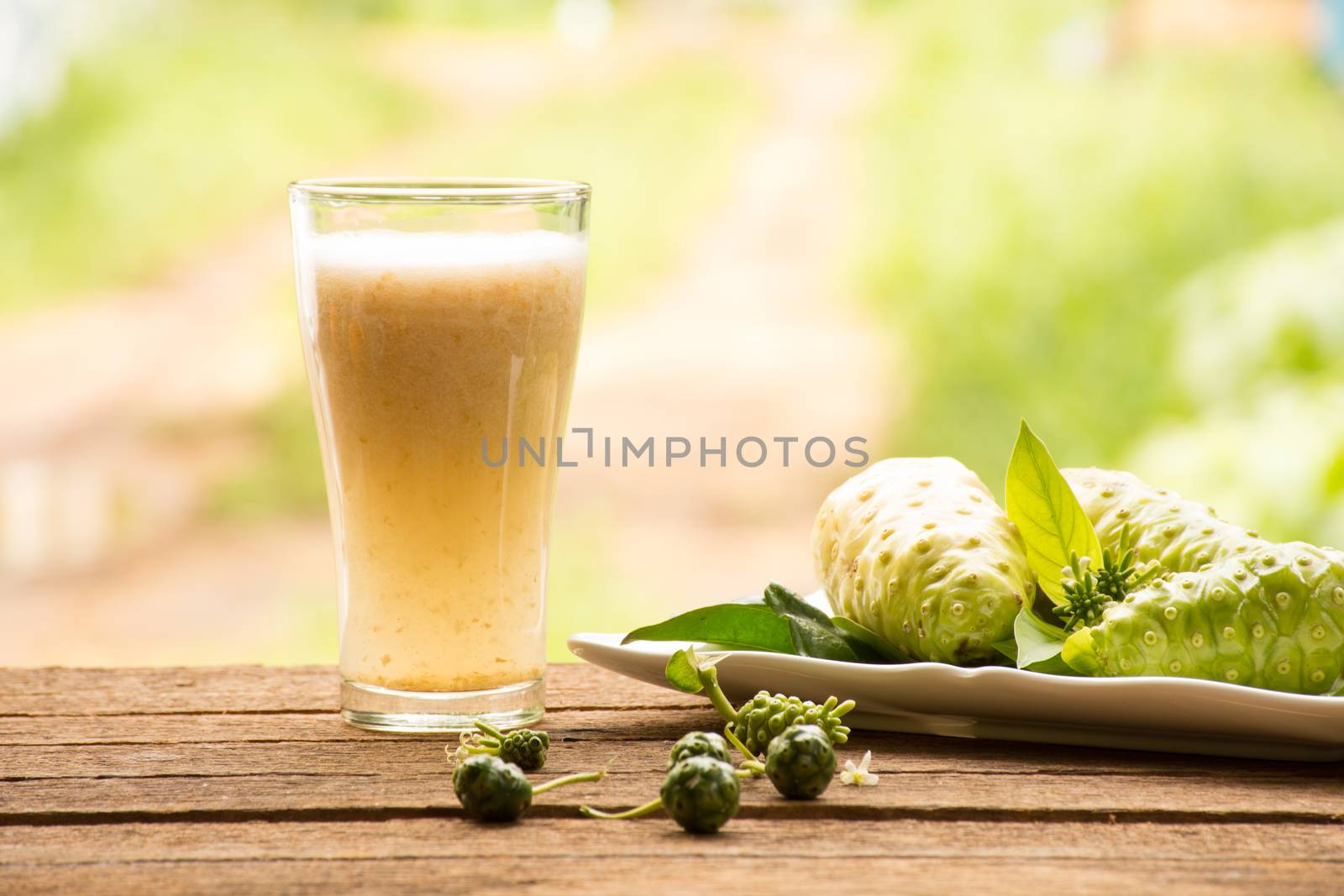 Noni and noni juice on wooden background.Juice for health or fruit for health or herb for health.Outdoor view1