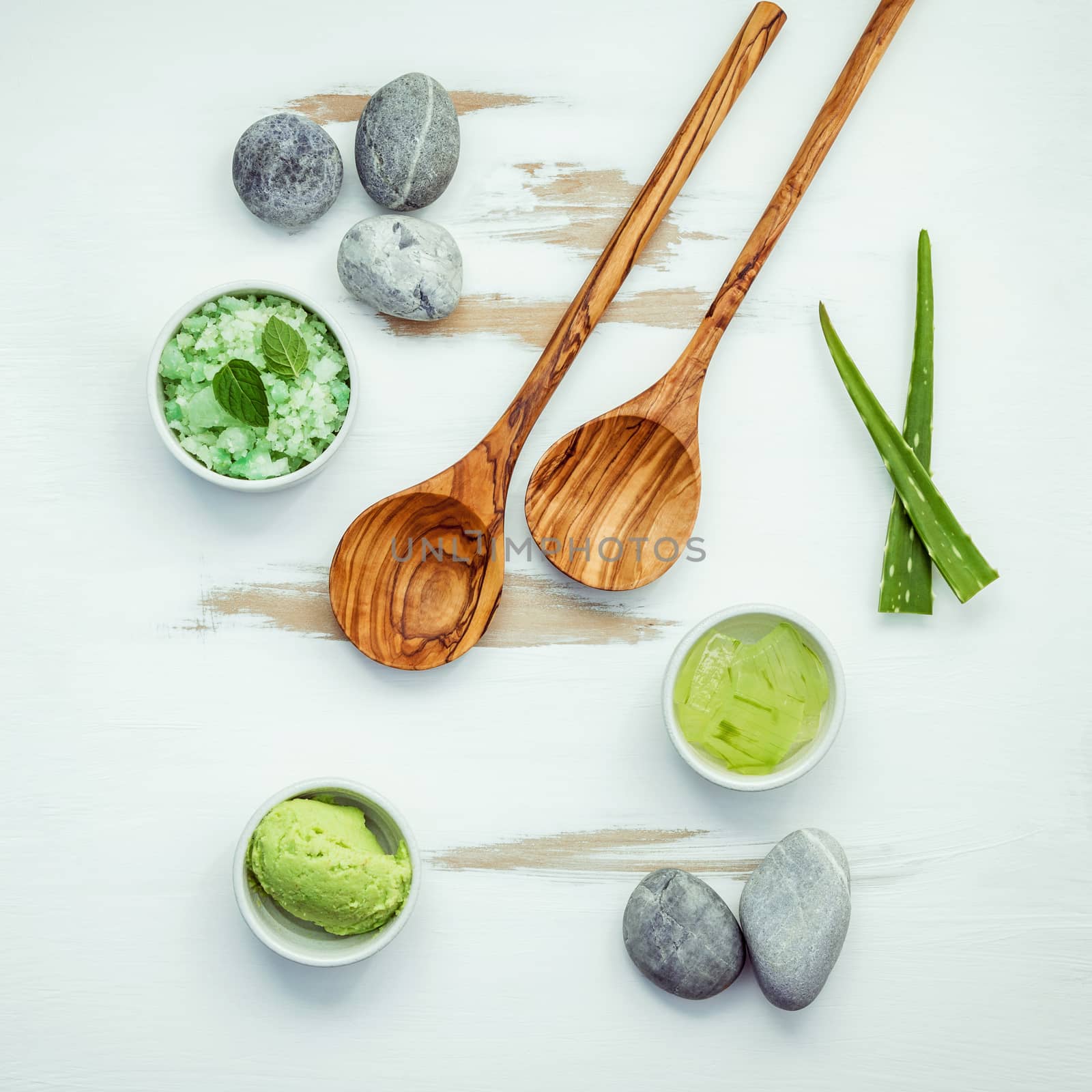 Homemade skin care and body scrubs with green natural ingredients aloe vera  ,aromatic salt ,avocado scrub and spa stone set up on white shabby wooden background. Zen spa and oriental spa theme.