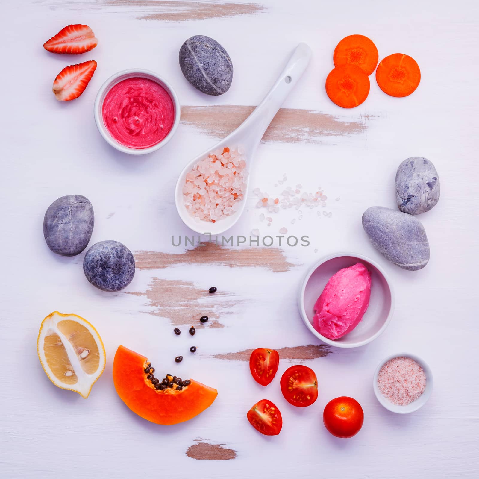Homemade skin care and body scrubs with red natural ingredients strawberry ,tomato ,himalayan salt, papaya, carrot and spa stone setup on white wooden background .Zen spa and oriental spa theme.