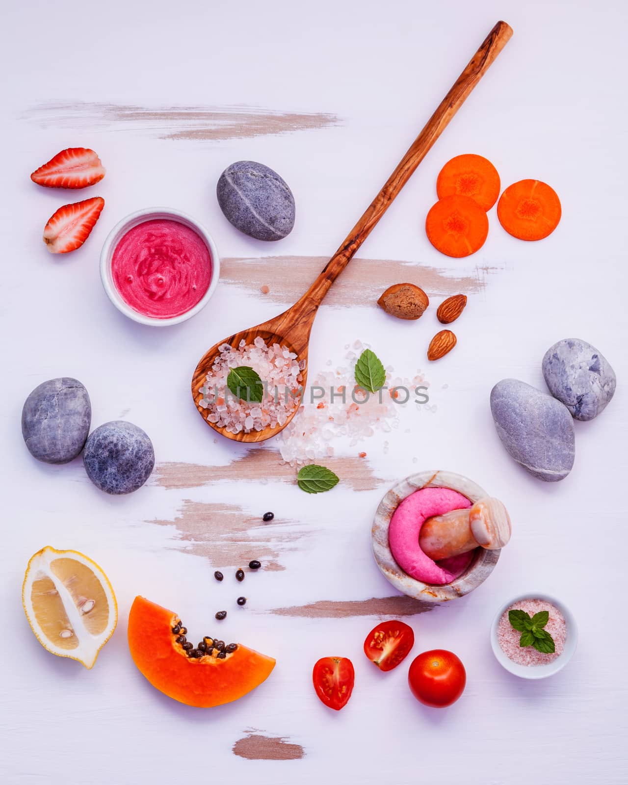Homemade skin care and body scrubs with red natural ingredients strawberry ,tomato ,himalayan salt, papaya, carrot and spa stone setup on white wooden background .Zen spa and oriental spa theme.