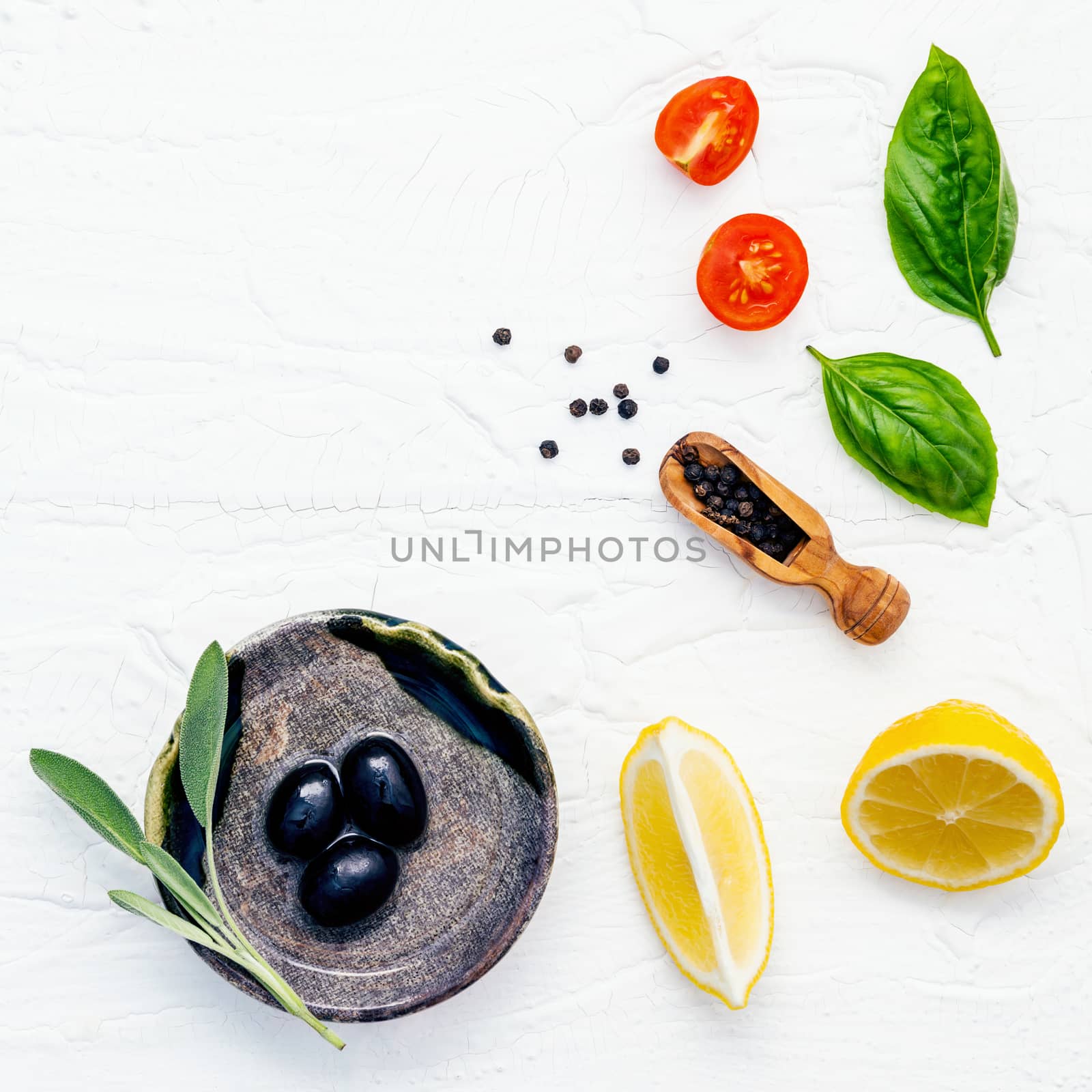 Food background with fresh herbs  tomato ,lemon slice , black pepper ,sage leaves ,sweet basil and olive oil over white wooden background  with flat lay and copy space.